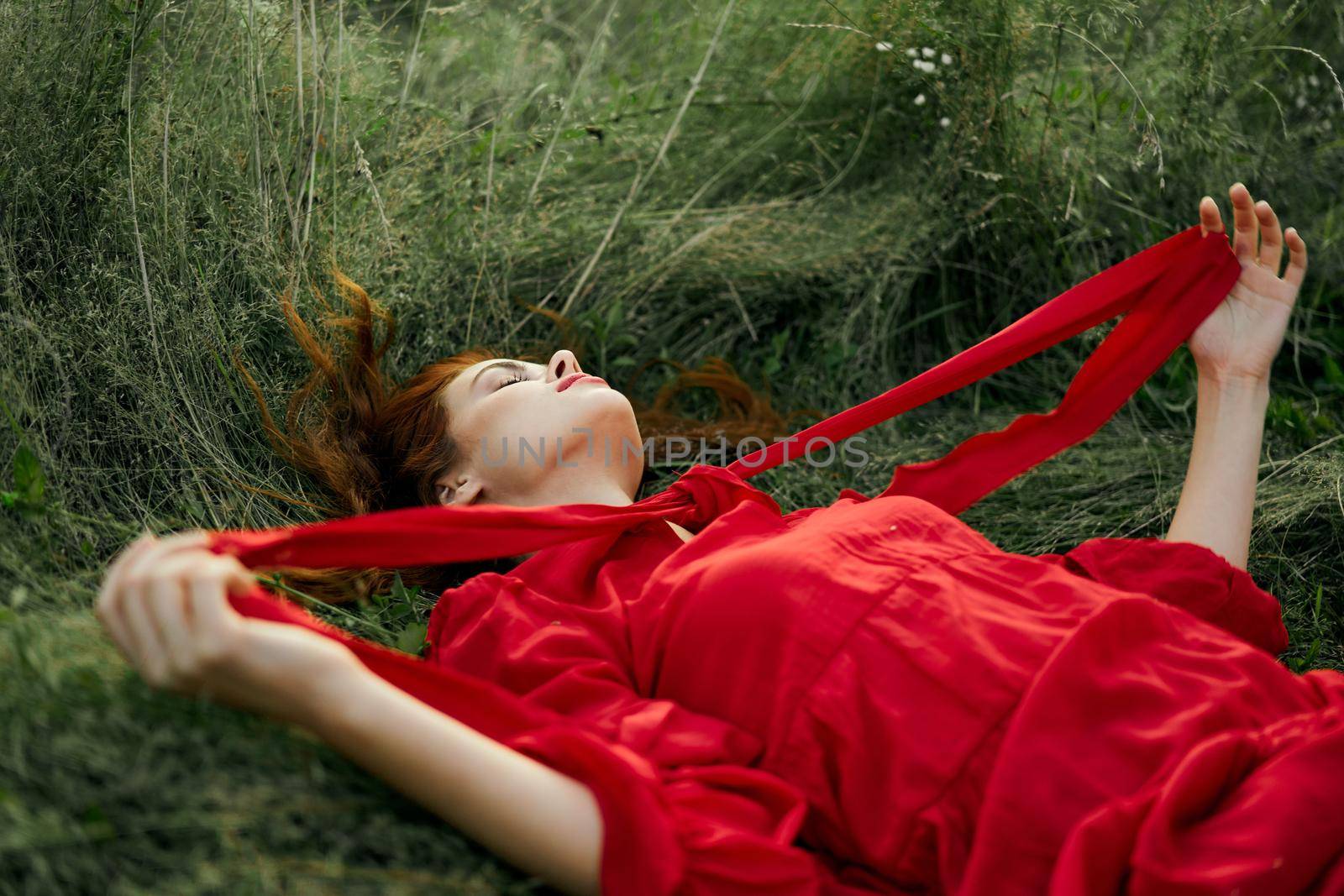 woman in red dress lying on the grass fresh air nature romance. High quality photo