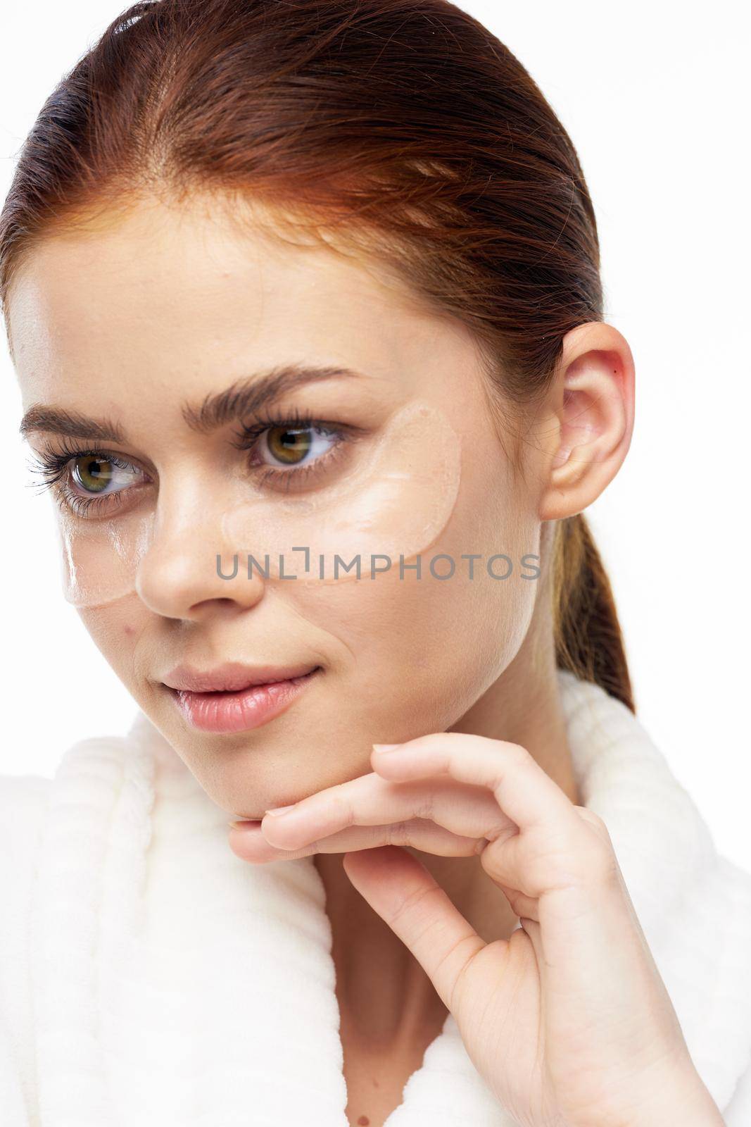 Woman in white robe posing fun skin care patches on face. High quality photo