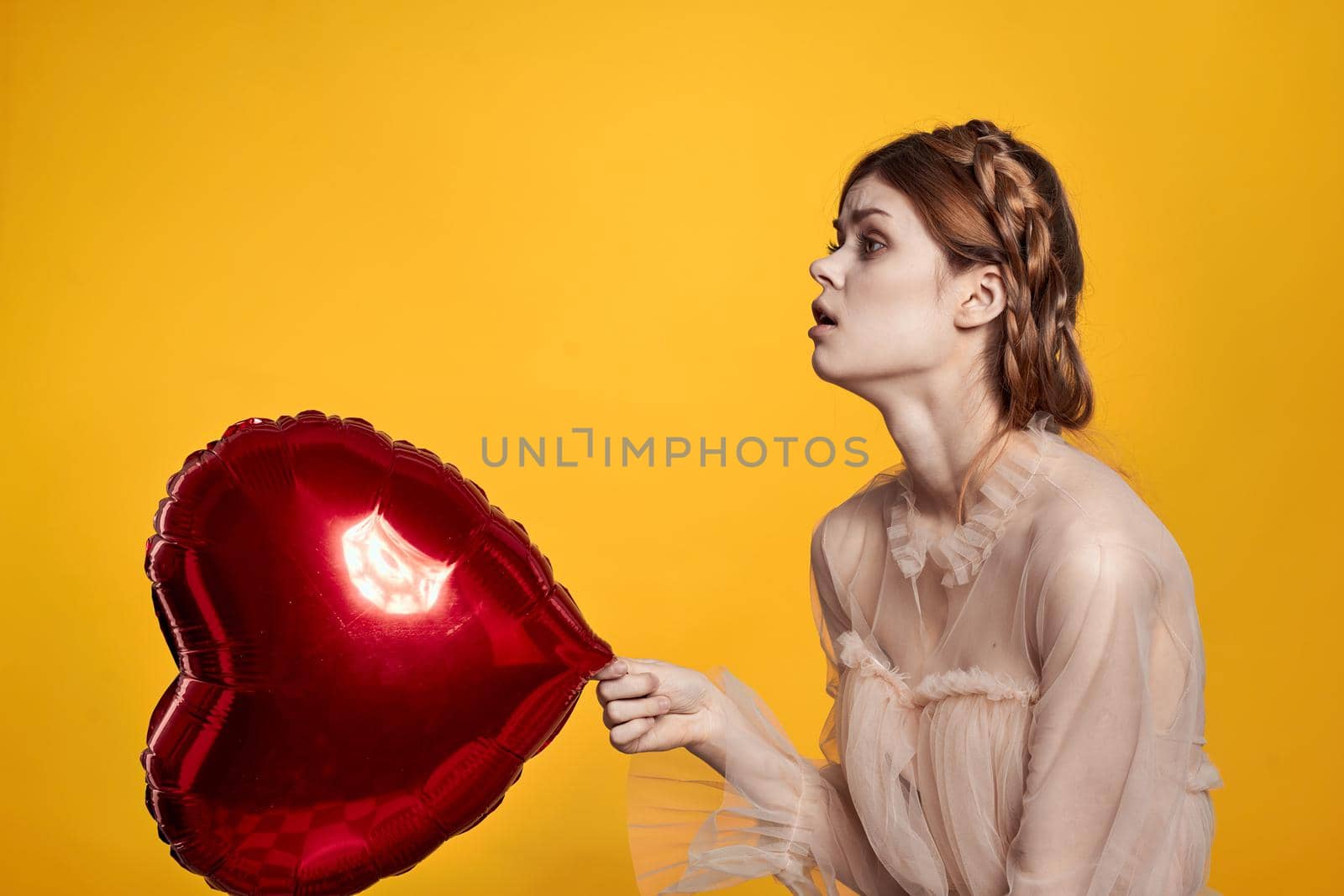 portrait of a woman Birthday party gift heart balloon yellow background. High quality photo
