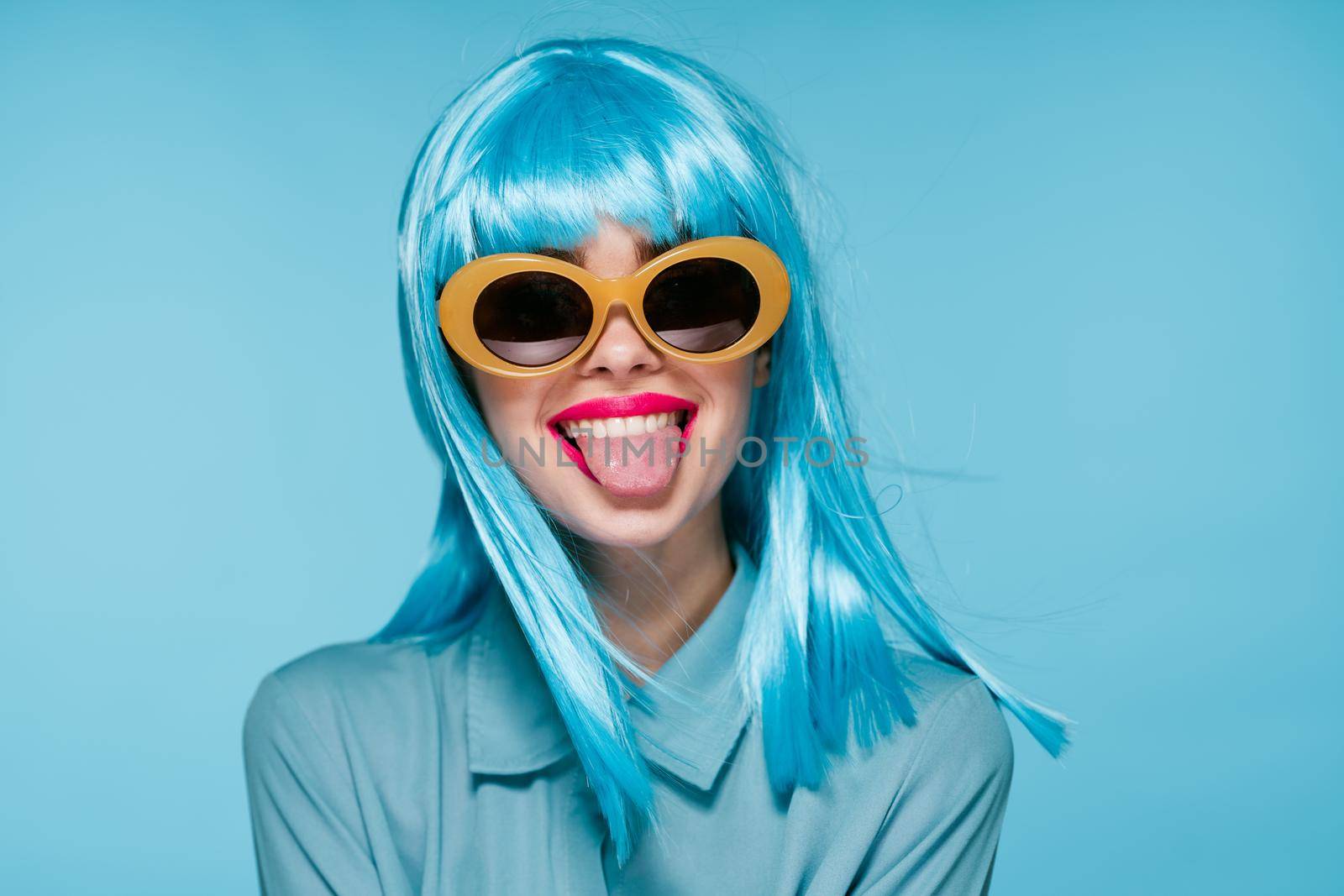 joyful woman purple wig fashion glasses hand gestures blue background. High quality photo