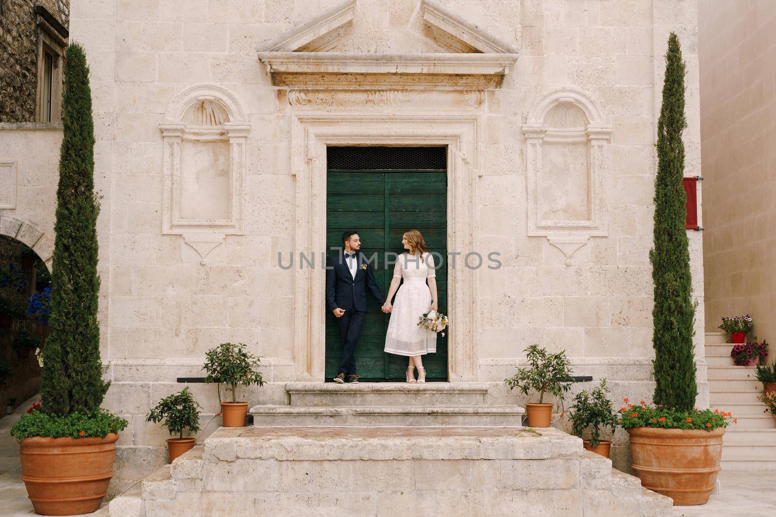 Bride and groom stand on the porch of the Church of St. Mark the Apostle. Montenegro. High quality photo