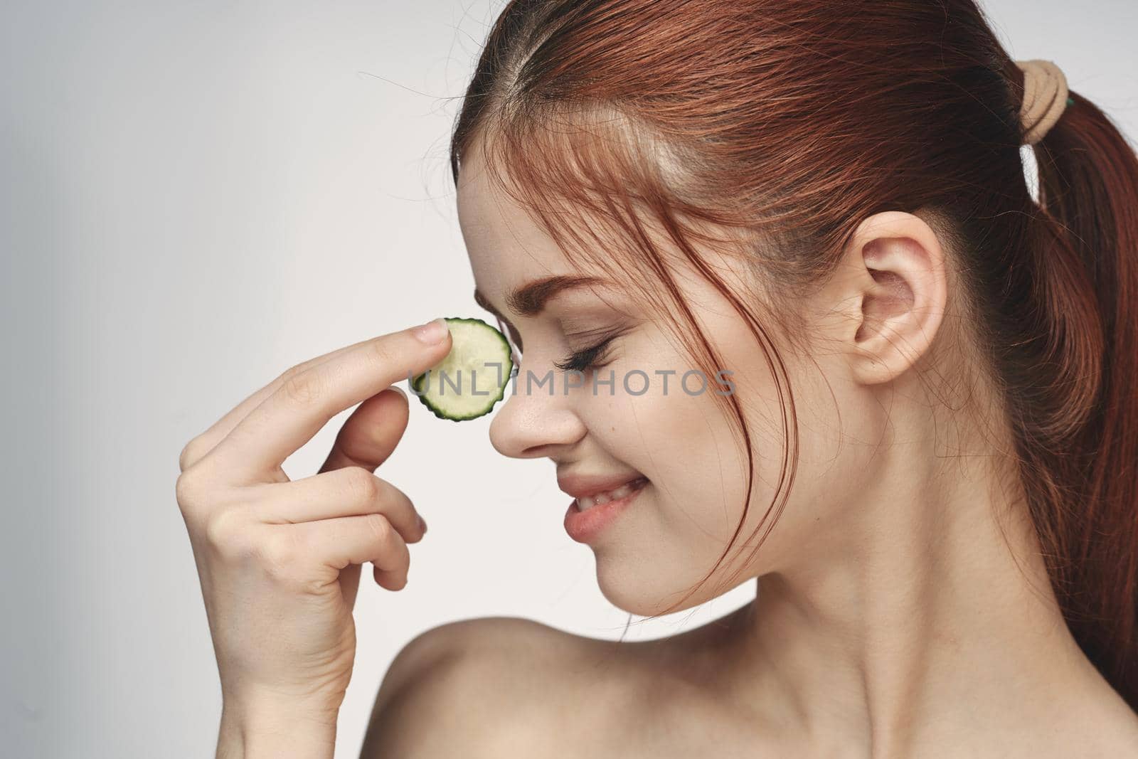 attractive woman with bare shoulders cucumber skin care health. High quality photo