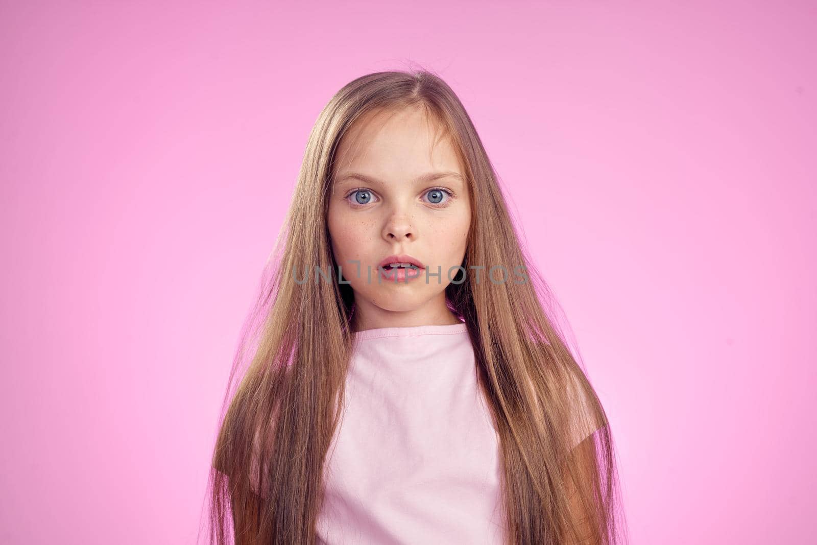 cute girl with long hair on pink background lifestyle childhood. High quality photo