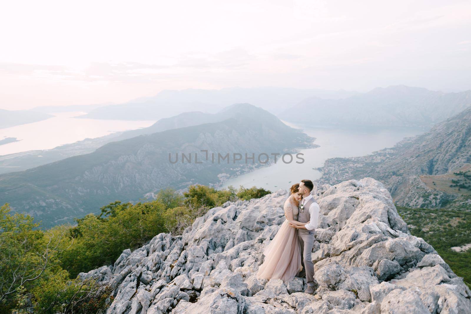 Groom embraces bride on the mountain against the background of the Kotor Bay. Drone. High quality photo