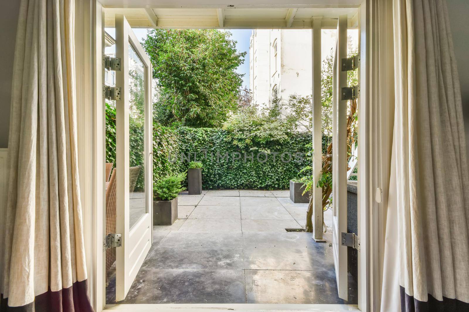 Open door with full length curtains leading to the courtyard of the house