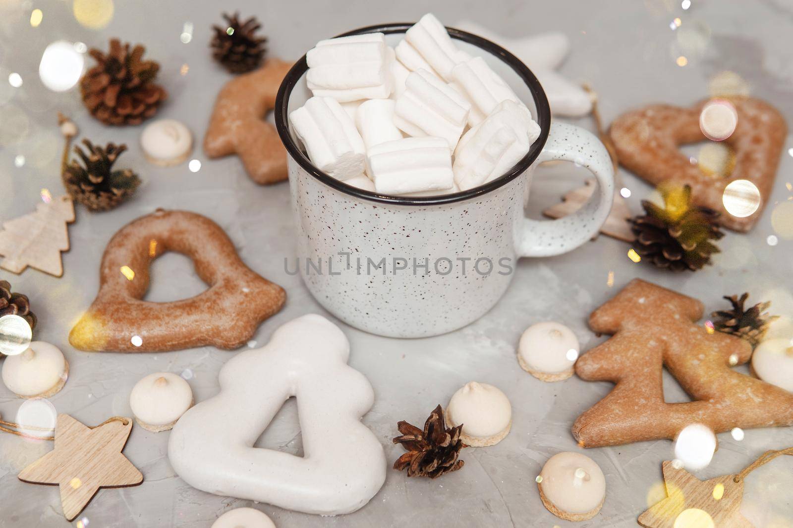 A cup of cocoa with marshmallows and Christmas gingerbread on the table, bokeh lights in the foreground. The concept of desserts and drinks during the Christmas holidays.