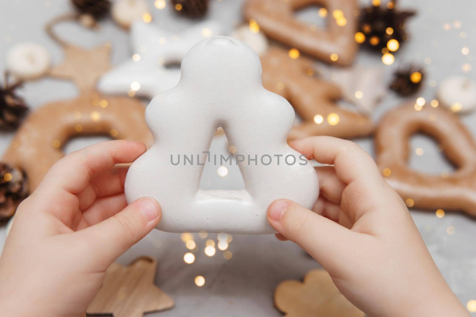 Children's hands hold a gingerbread in the shape of a Christmas tree. The concept of Christmas sweets, toys, garlands and bokeh. Decor for New Year holidays.