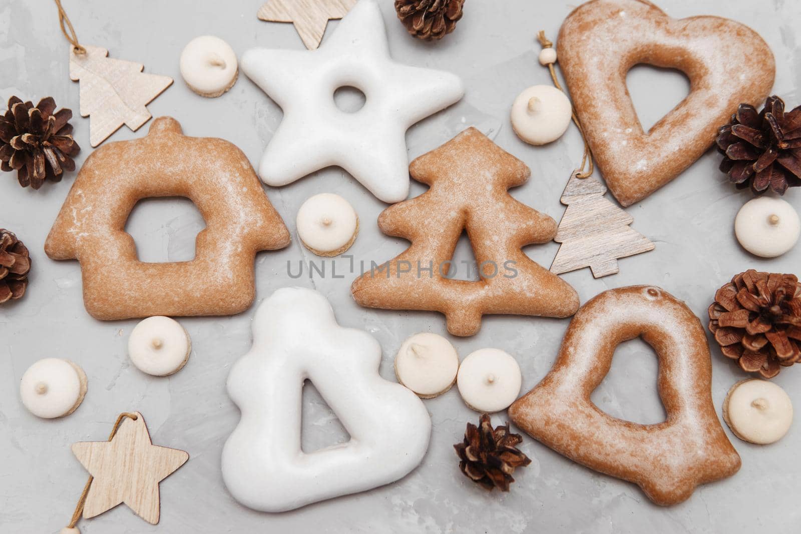 Banner for Christmas and New Year gingerbread stars, houses, Christmas trees, toys on a gray concrete background, Christmas lights bokeh in the foreground.