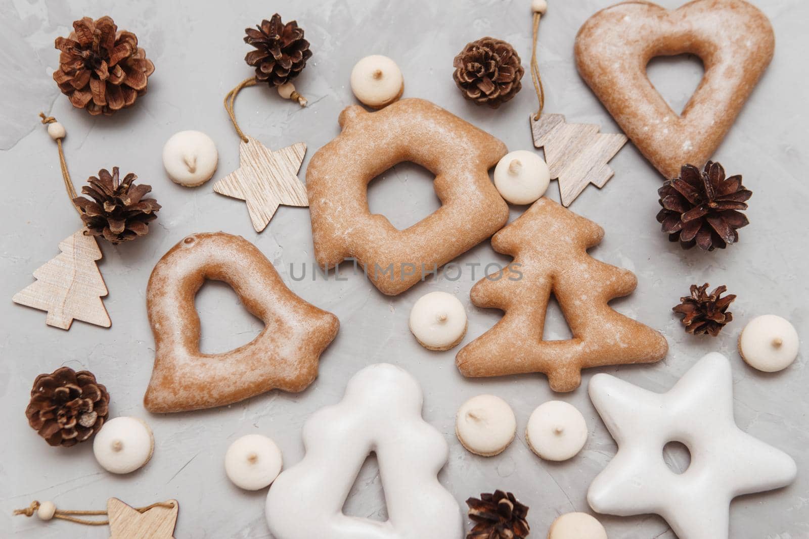 Banner for Christmas and New Year gingerbread stars, houses, Christmas trees, toys on a gray concrete background, Christmas lights bokeh in the foreground.