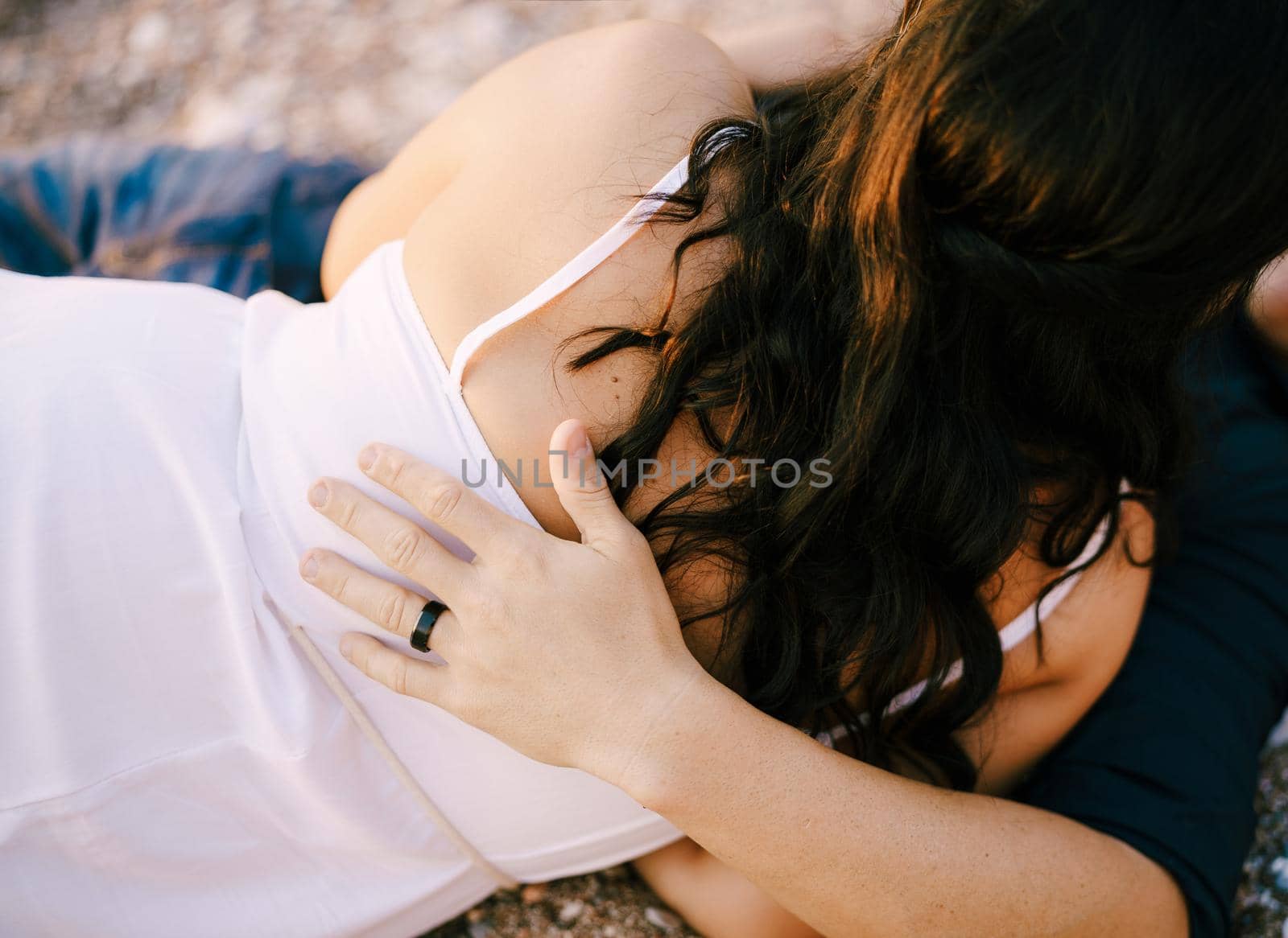 Man and woman hugging while lying on the gravel path in the park. High quality photo