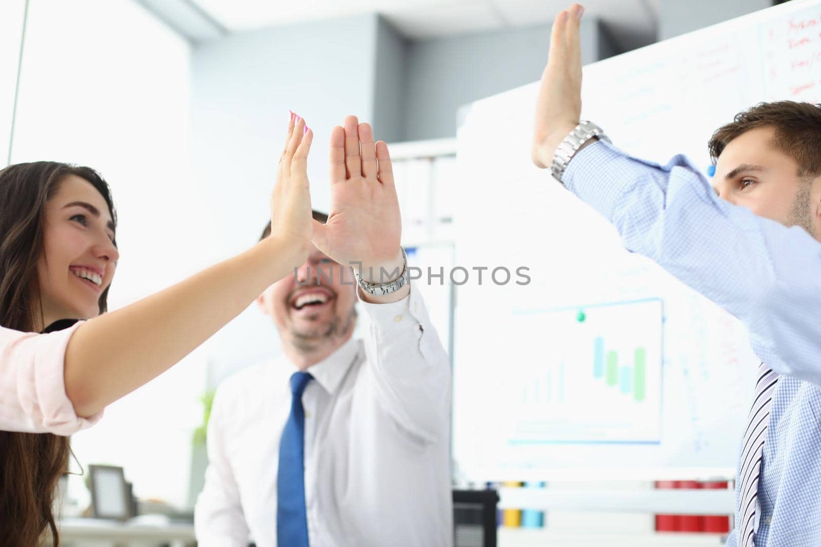 Portrait of team clapping hands together giving high five to celebrate finished business project. Successful teamwork in company office. Success concept