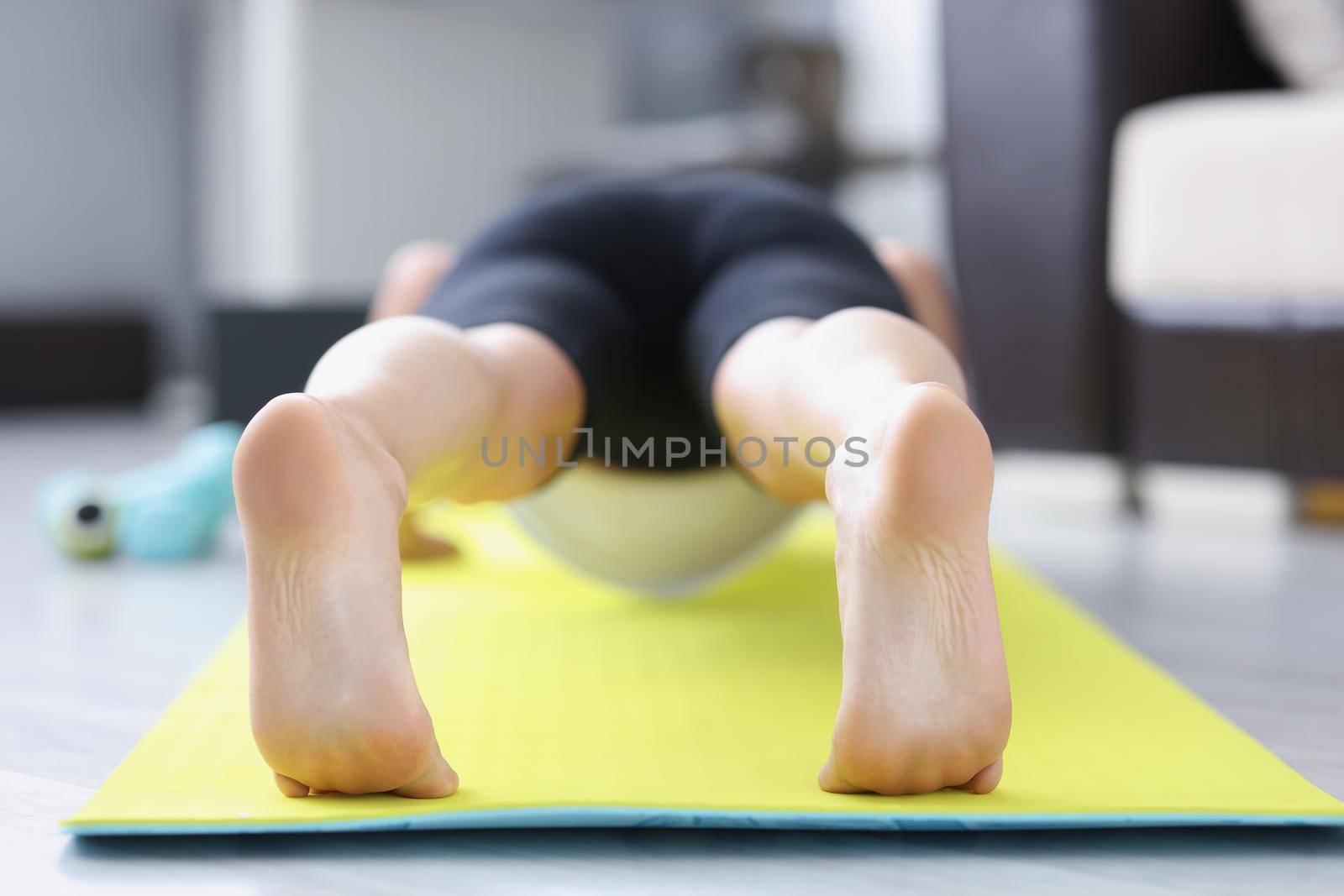 Low angle of male barefoot feet on mat performing exercise in morning for health. Good habit doing sport or yoga after waking up. Lifestyle, hobby concept