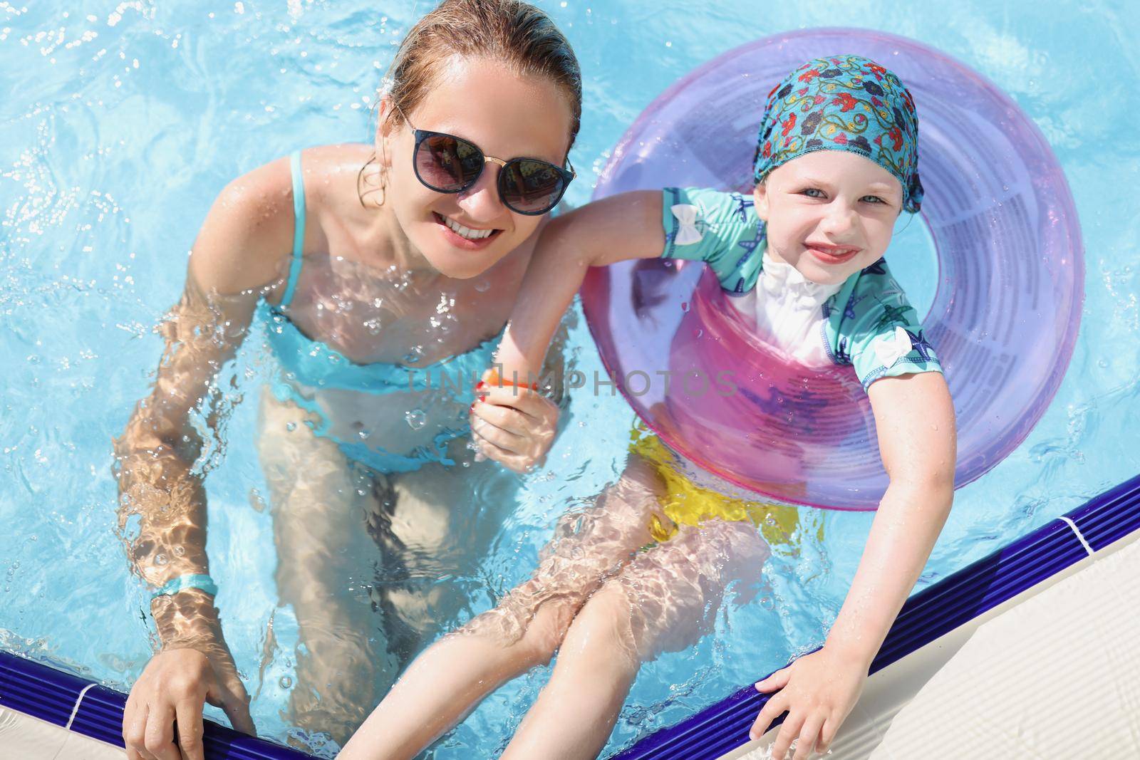 Top view of mother and daughter swimming in pool enjoy summer holiday. Smiling and happy parent and child on resort. Summer, childhood, parenthood concept