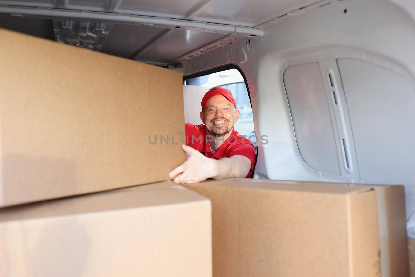 Cheerful man on work put boxes in truck for further delivery on address by kuprevich