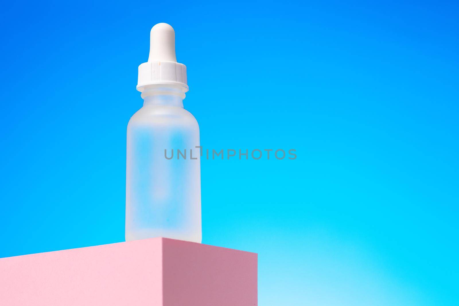 Beauty oil bottle with pipette against blue background close up