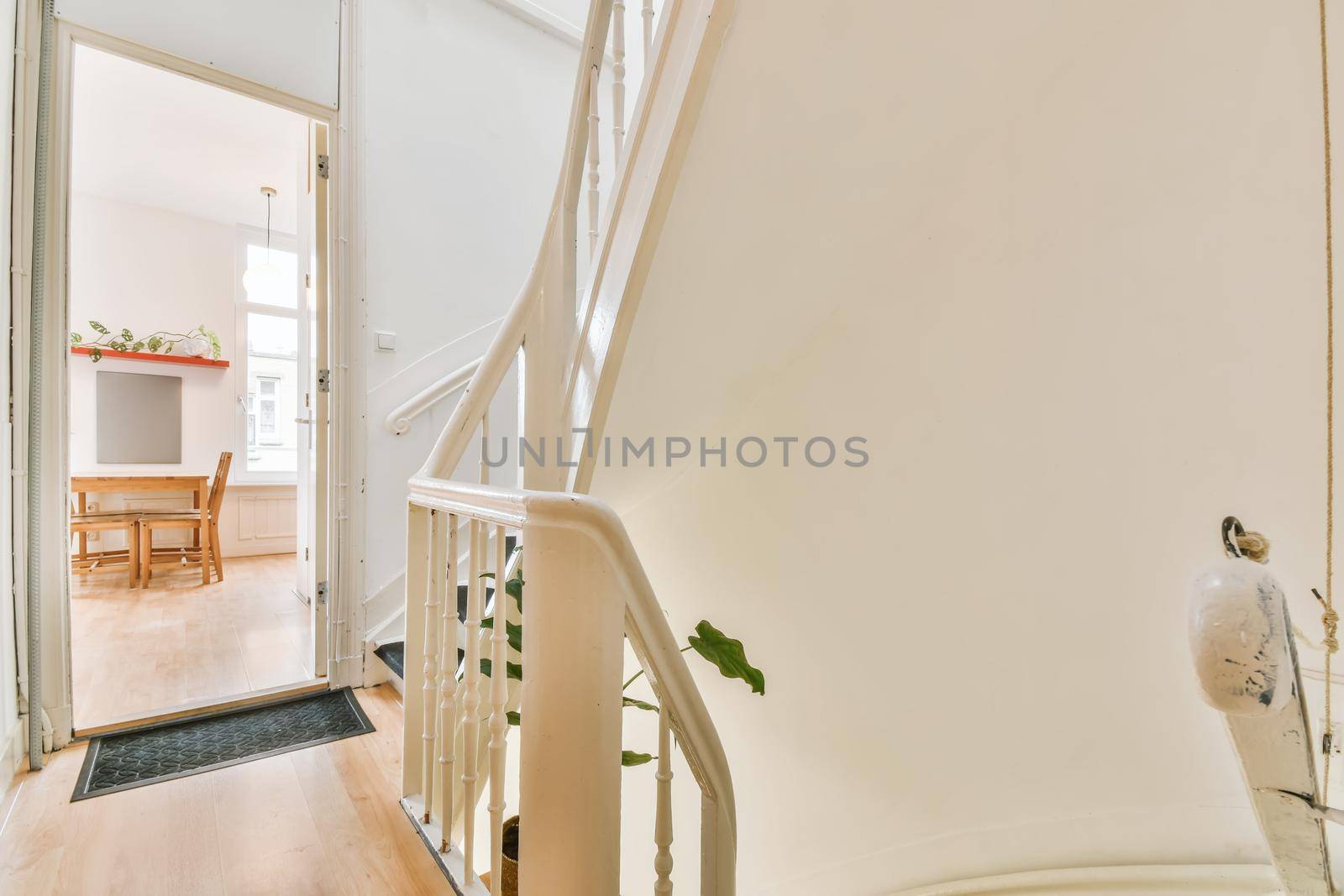 White spiral stairway connecting levels of contemporary house with wooden floor and white walls