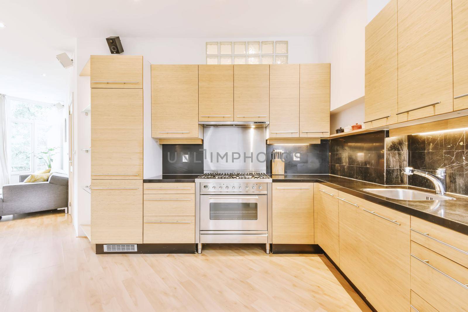 Interior of contemporary open plan kitchen with built in appliances and cabinets under ceiling with wooden beams in light