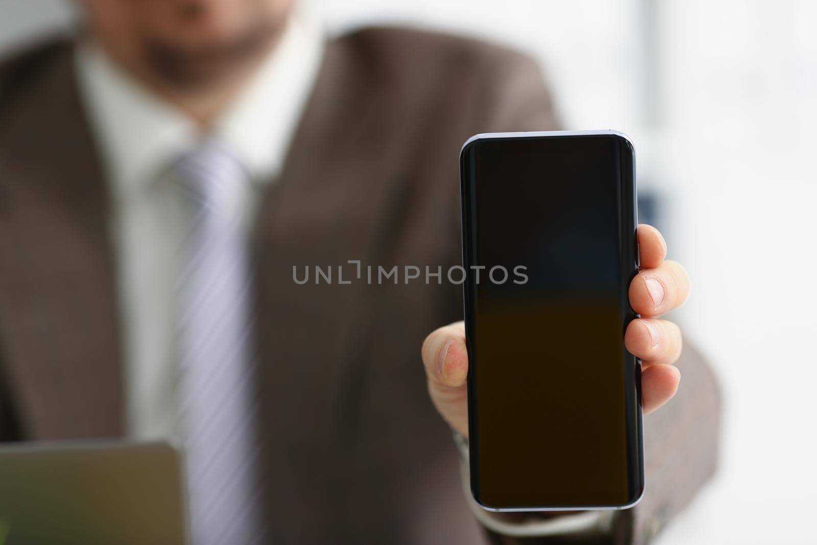 Close-up of male arm in suit show in camera mobile phone display with black screen. Broken or locked smartphone, not working. Mockup, copy space concept