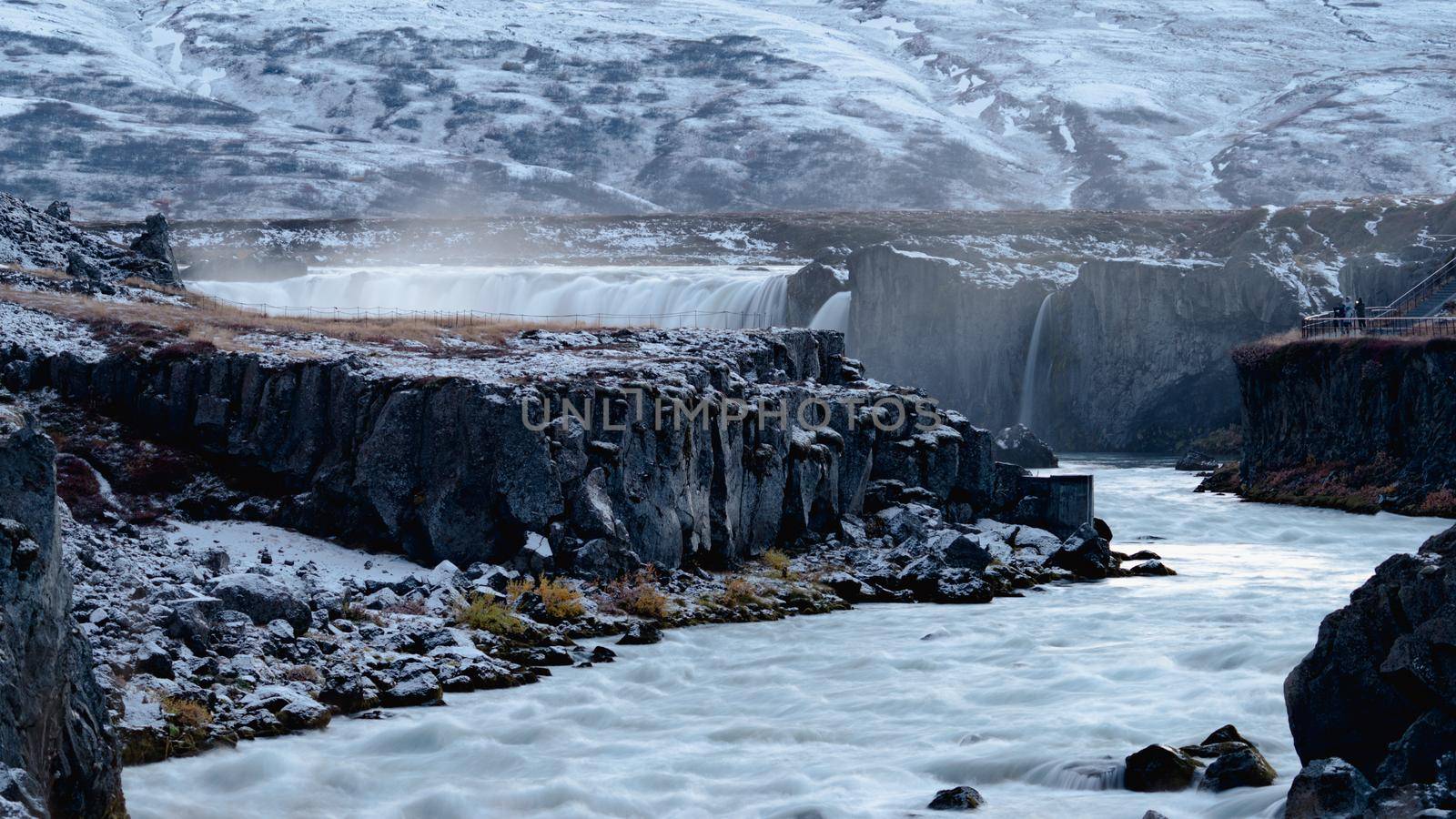 Long shot silk water of Godafoss on autumn with snow, Icelandic waterfall