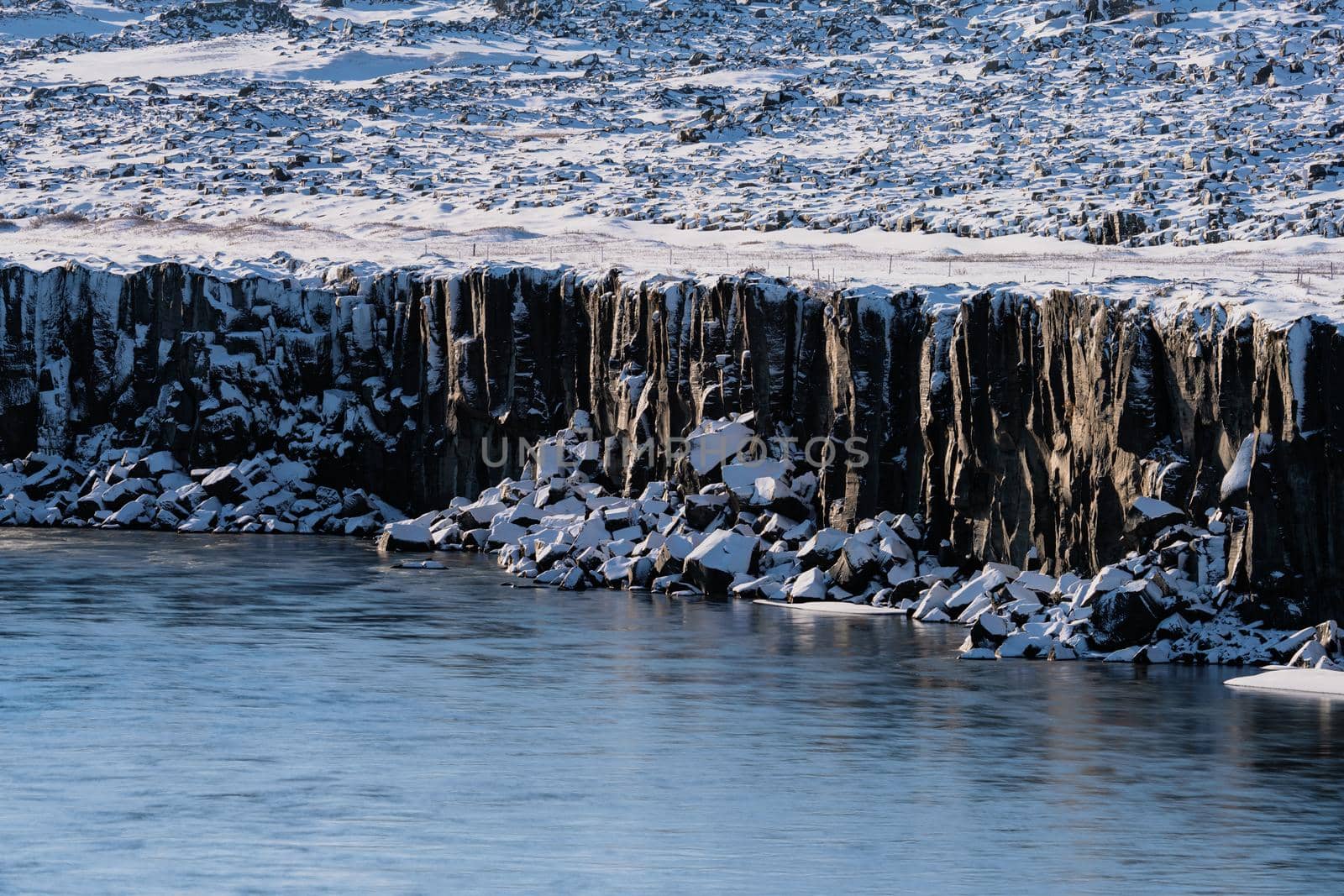 Snow covered boulder cubes under the cliffs to the river