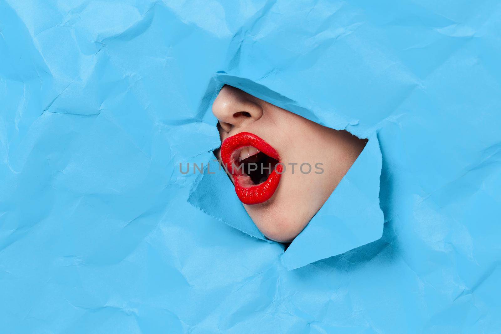 woman's face breaks through blue mockup close-up. High quality photo