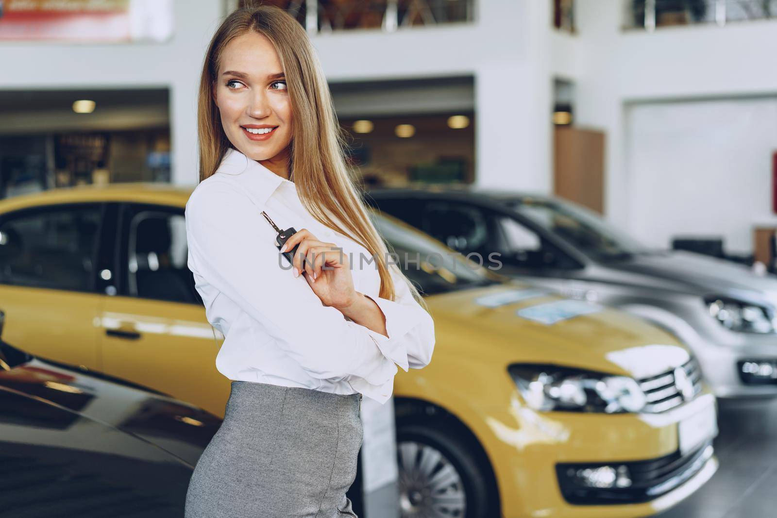 Young happy woman buyer/seller near the car with keys in hand close up