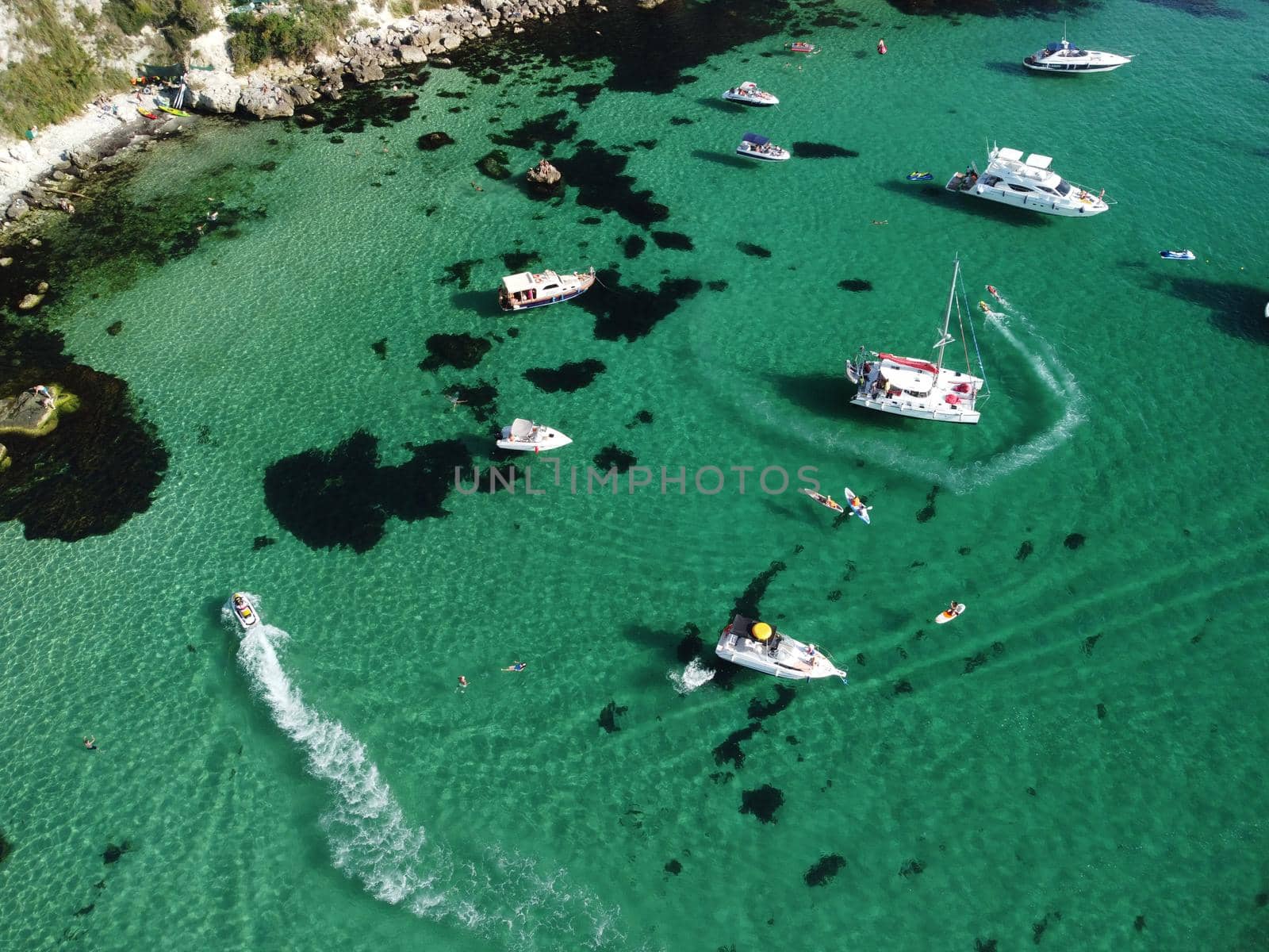 Sea landscape with rocky coastline on sunset time with cloudy sky. Yachts in the Sea on a background of rocky shores. The concept of perfect place for summer travel and rest.