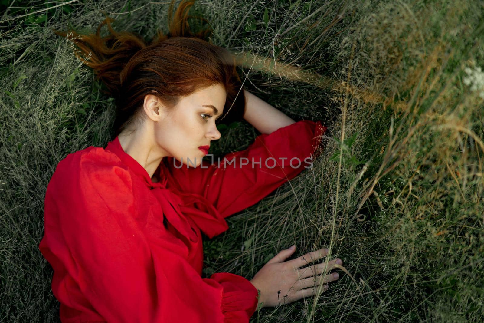 pretty woman in red dress lies on the grass sun summer nature by Vichizh