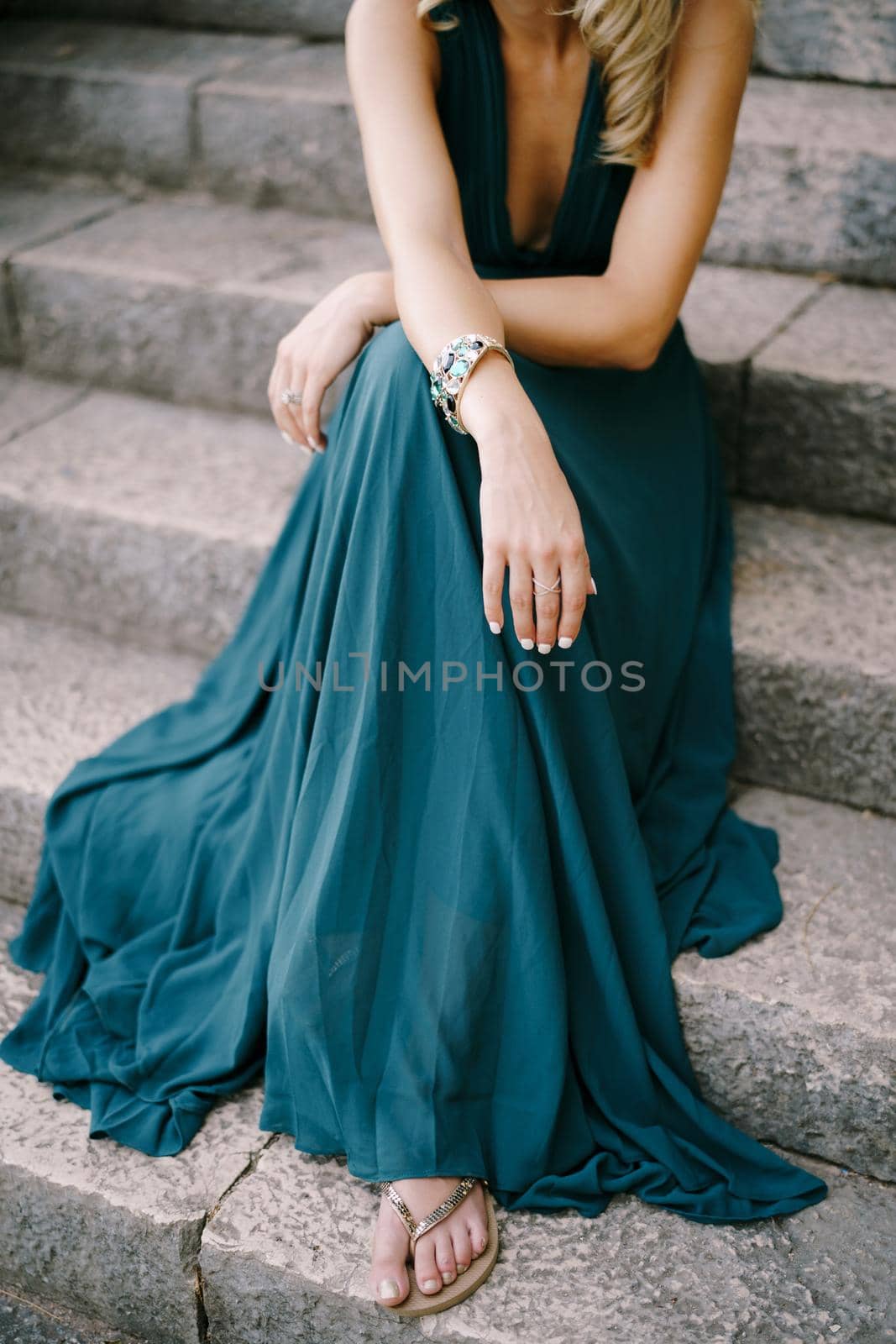 Woman in a green dress sits on the stone steps. Close-up. High quality photo
