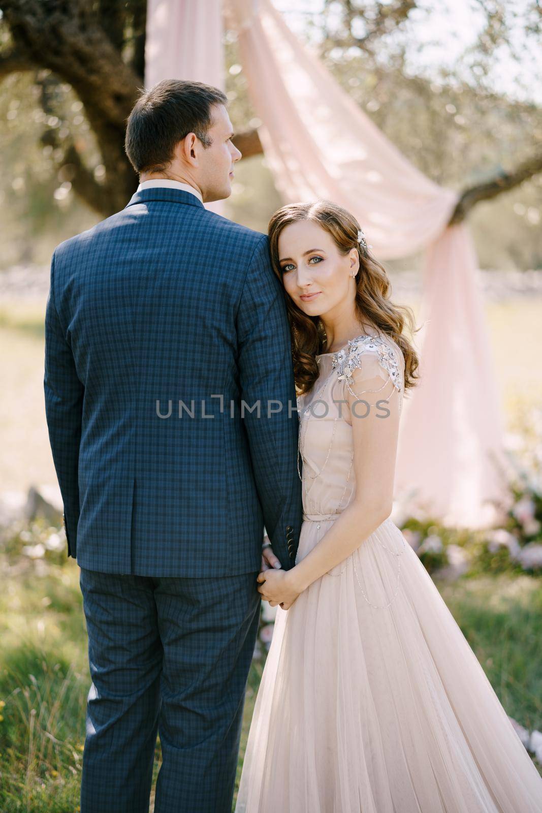 Bride holds groom hand, resting her head on his shoulder. High quality photo
