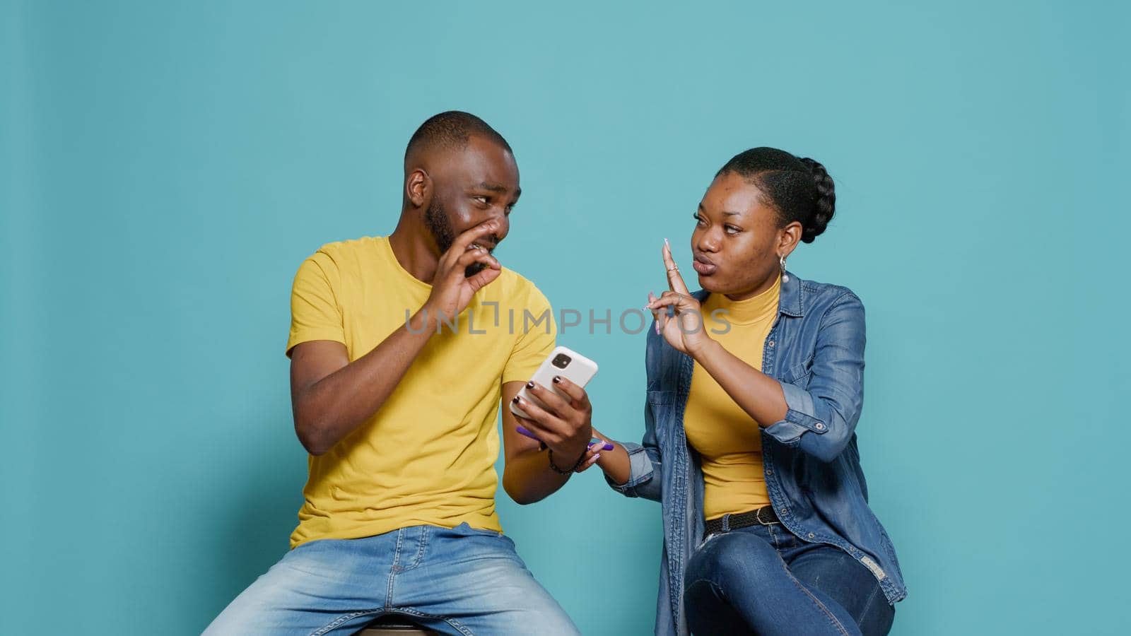 Man and woman using mobile phone to have fun together in studio by DCStudio