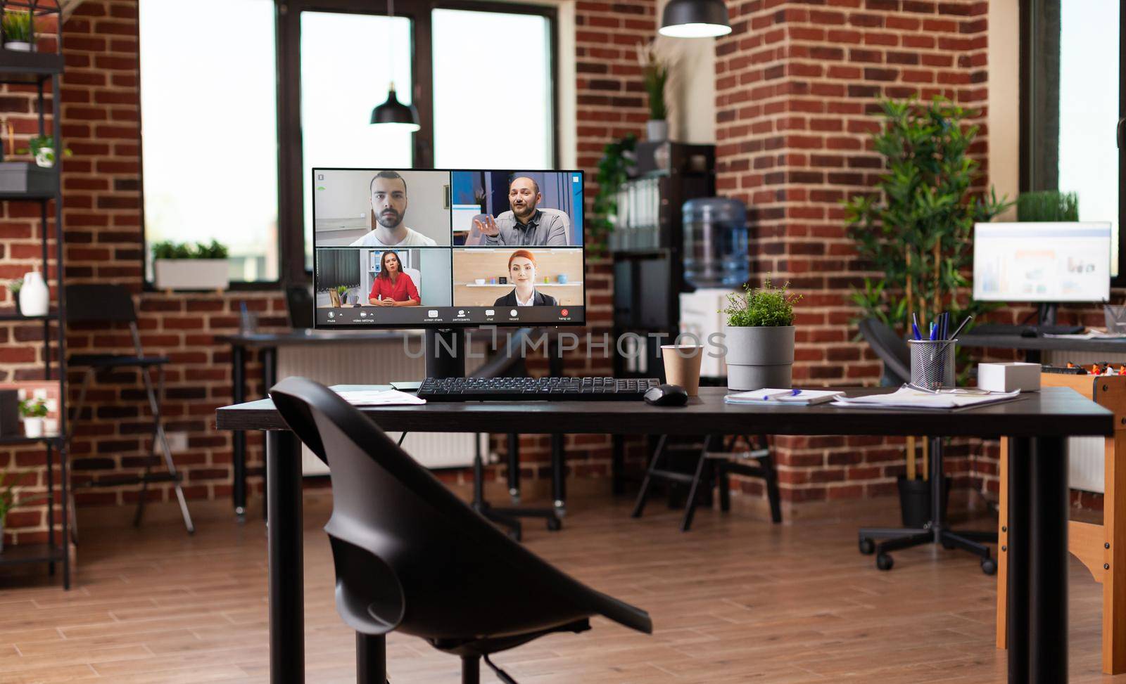 Monitor with video call conference on table in empty workplace by DCStudio