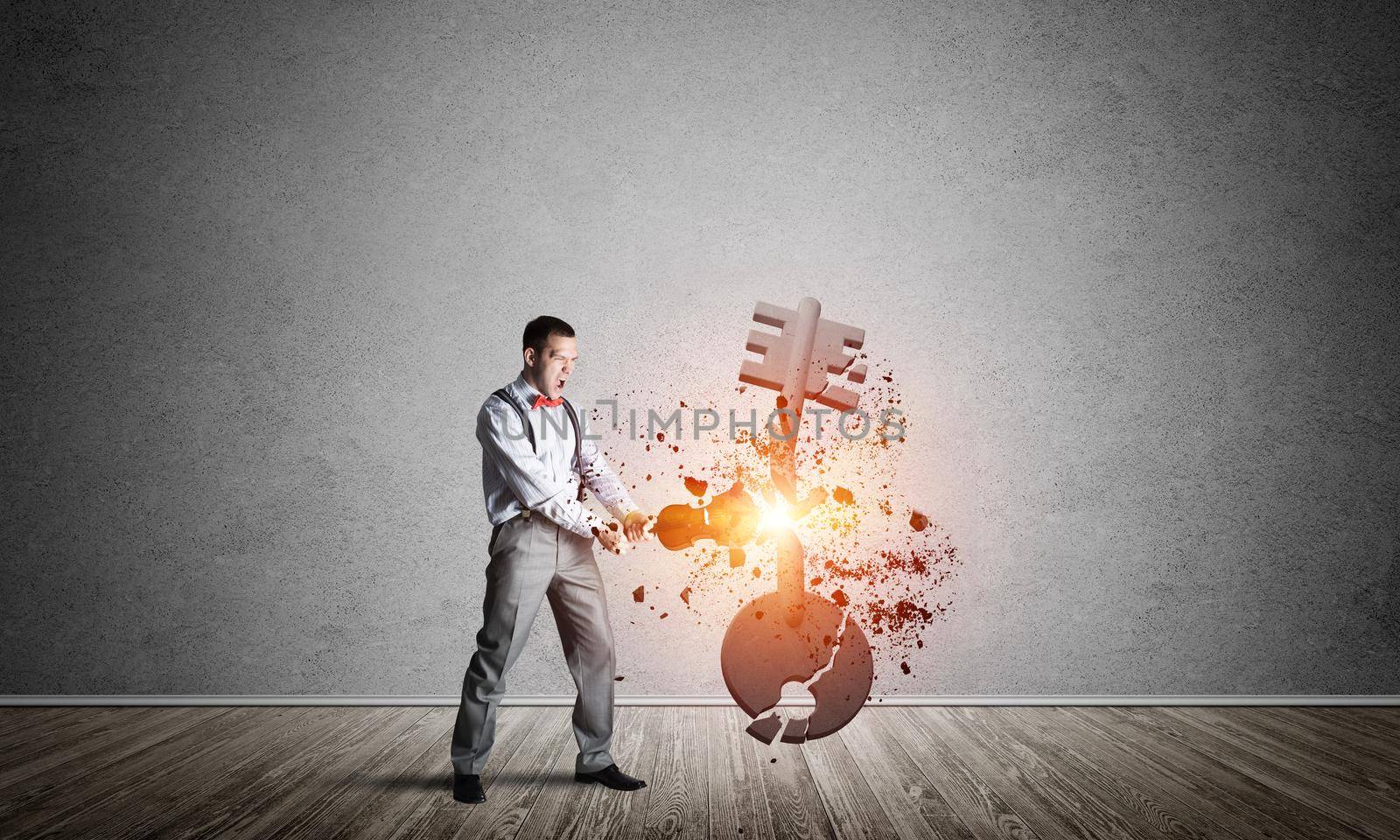 Determined businessman in empty interior breaking with violin stone key figure