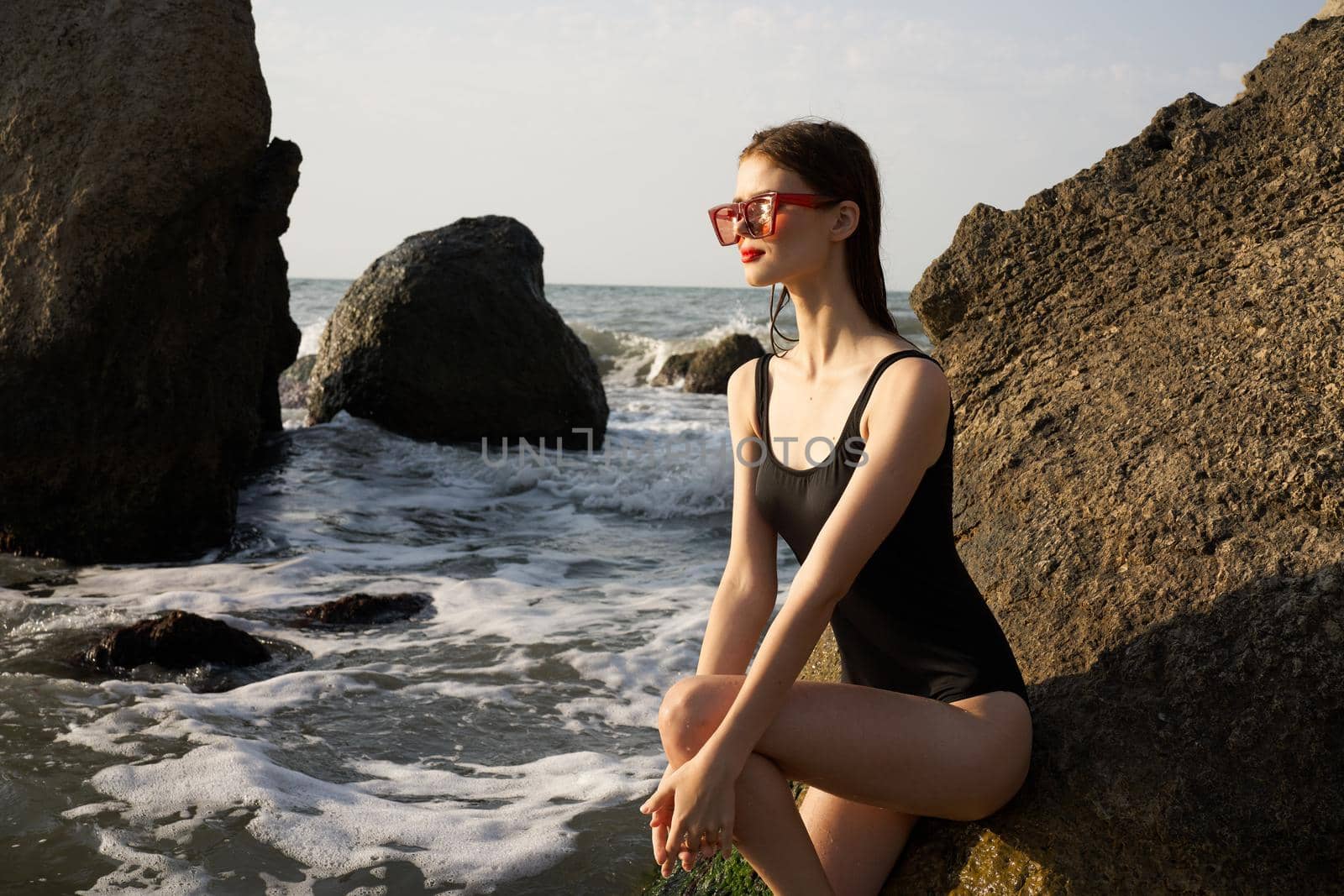 woman in black swimsuit posing near rocks ocean exotic by Vichizh