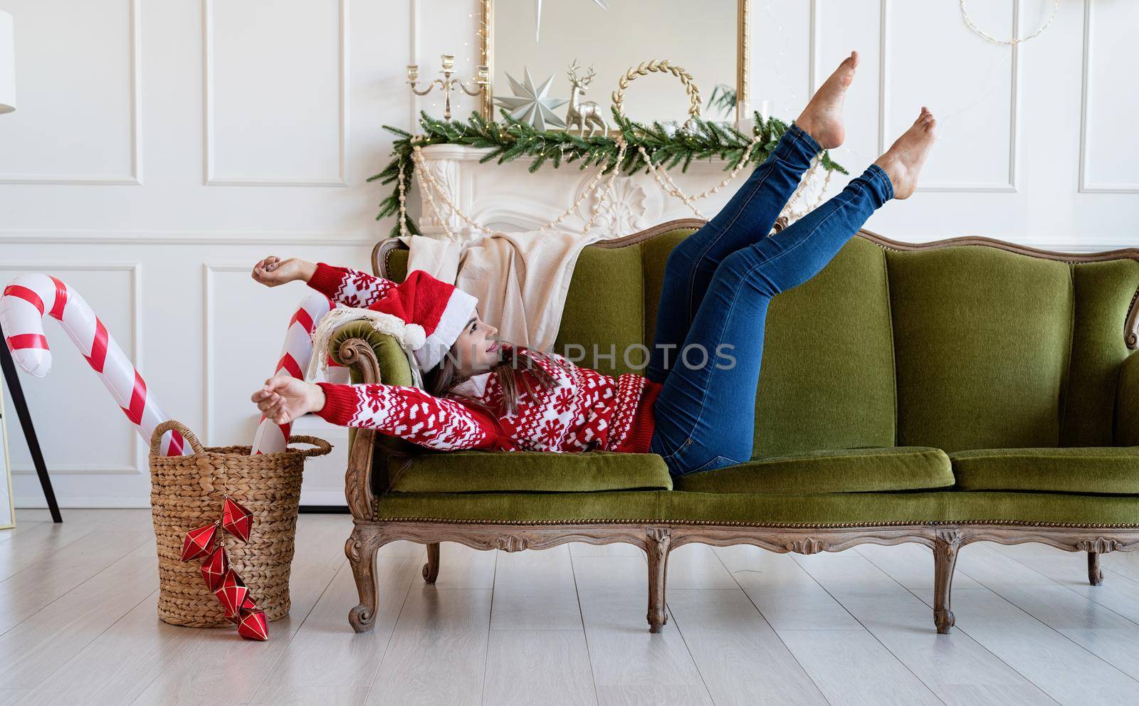 Young woman lying on couch alone in a decorated for Christmas living room by Desperada