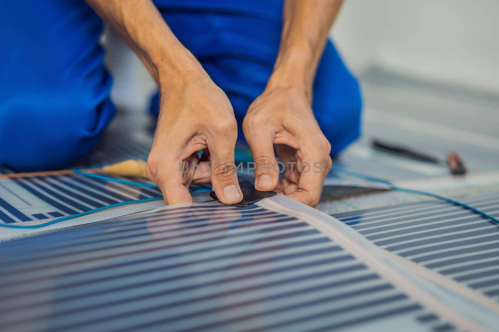 Master installs film warm floor in the room. Floor heating installation.