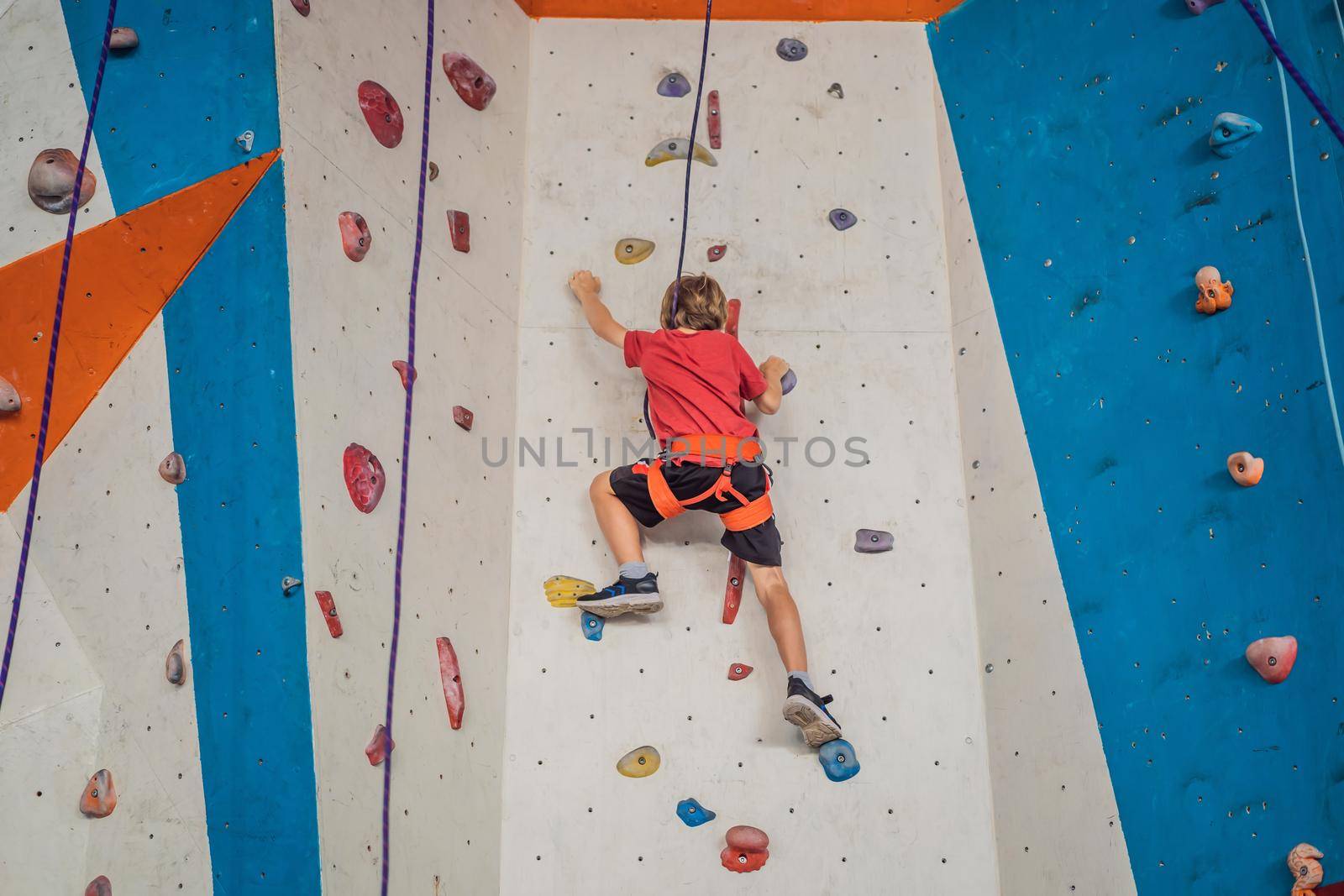 Boy at the climbing wall without a helmet, danger at the climbing wall.