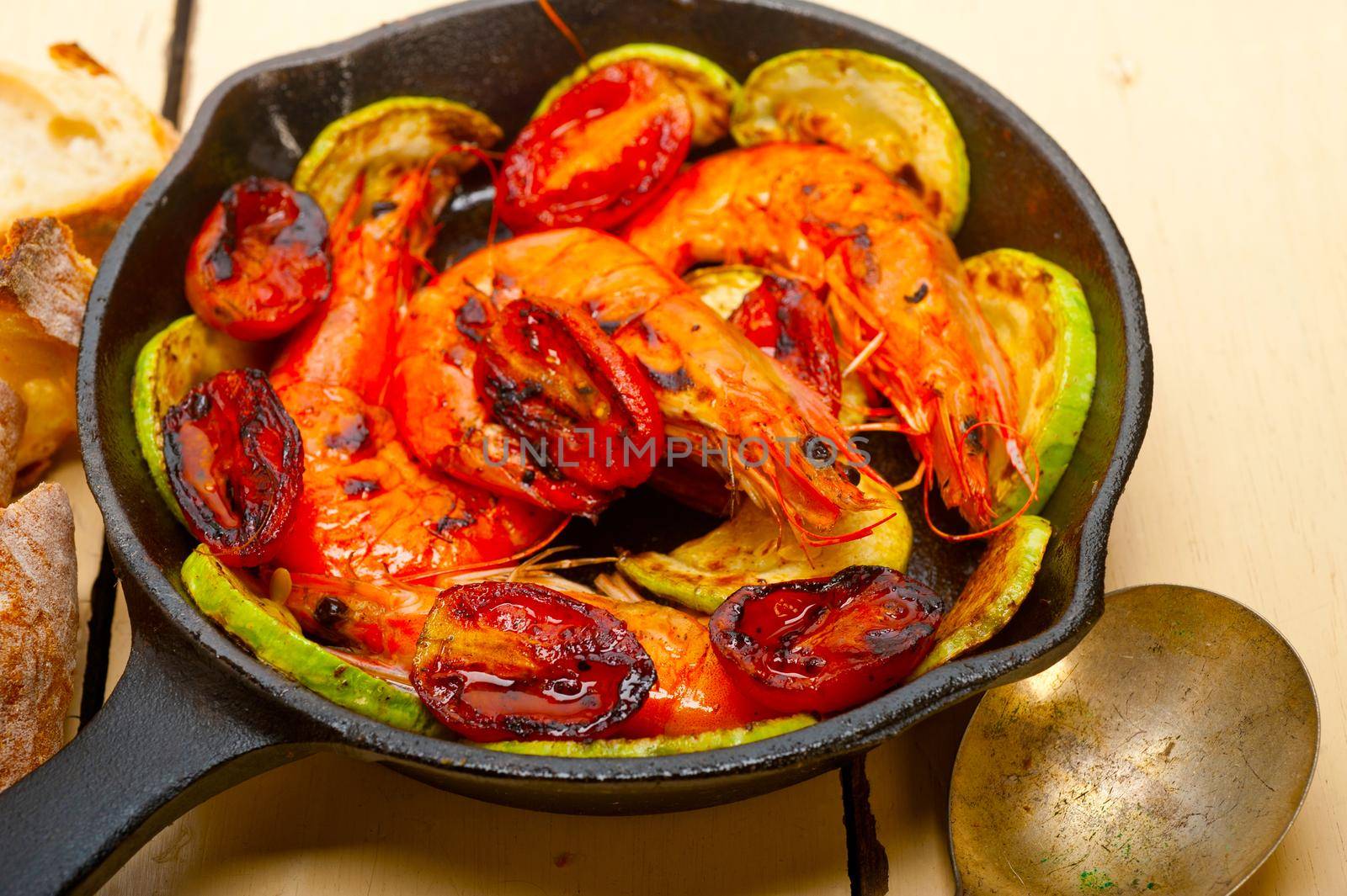 roasted shrimps on cast iron skillet  with zucchini and tomatoes