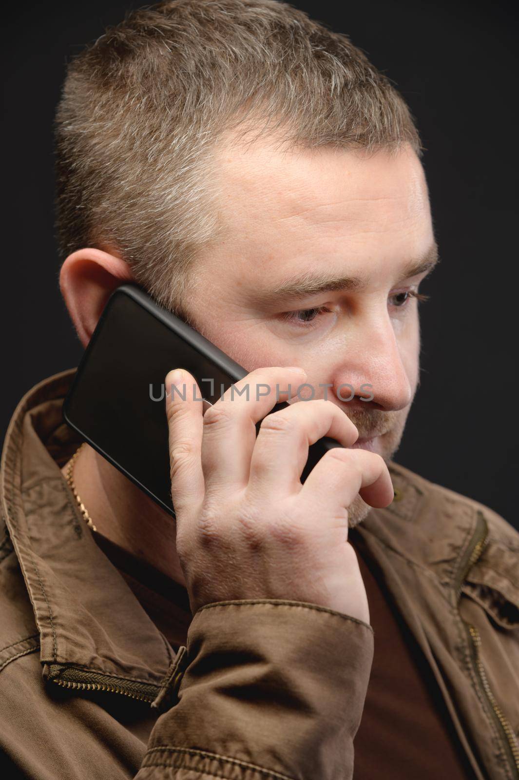 An anxious middle-aged man calls and talks on the phone. Close-up. Studio portrait.