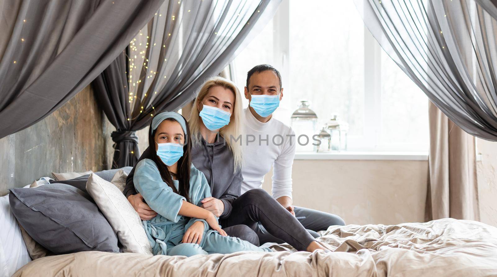 Affectionate young mother embracing little kid daughter, family wearing medical face mask, give support, comforting, expressing love. Concept of coronavirus or COVID-19 pandemic disease symptoms by Andelov13