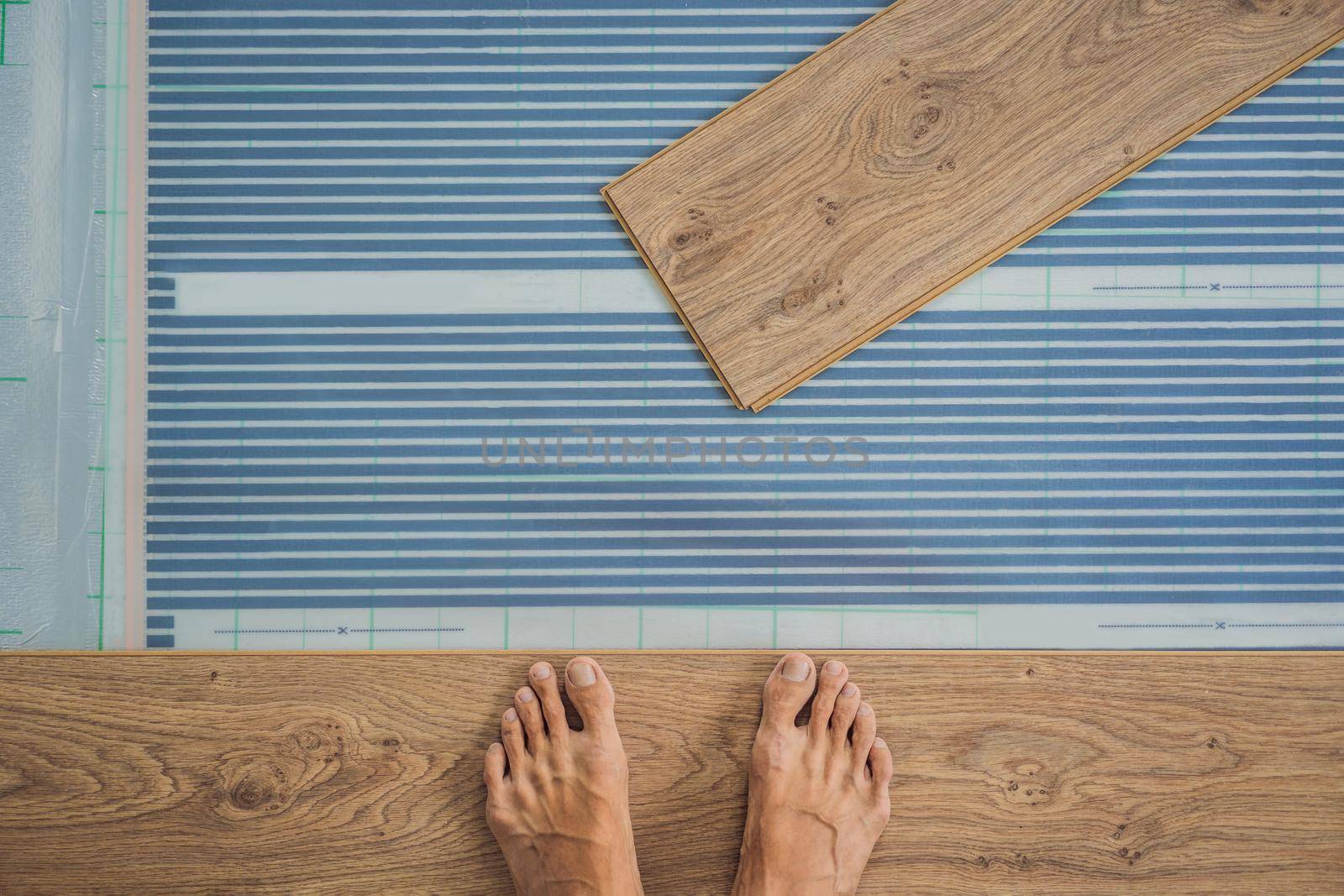 Wooden floor, laminate on a warm film floor. Comfort in home. Warm floor concept. Heating in the house and apartment.