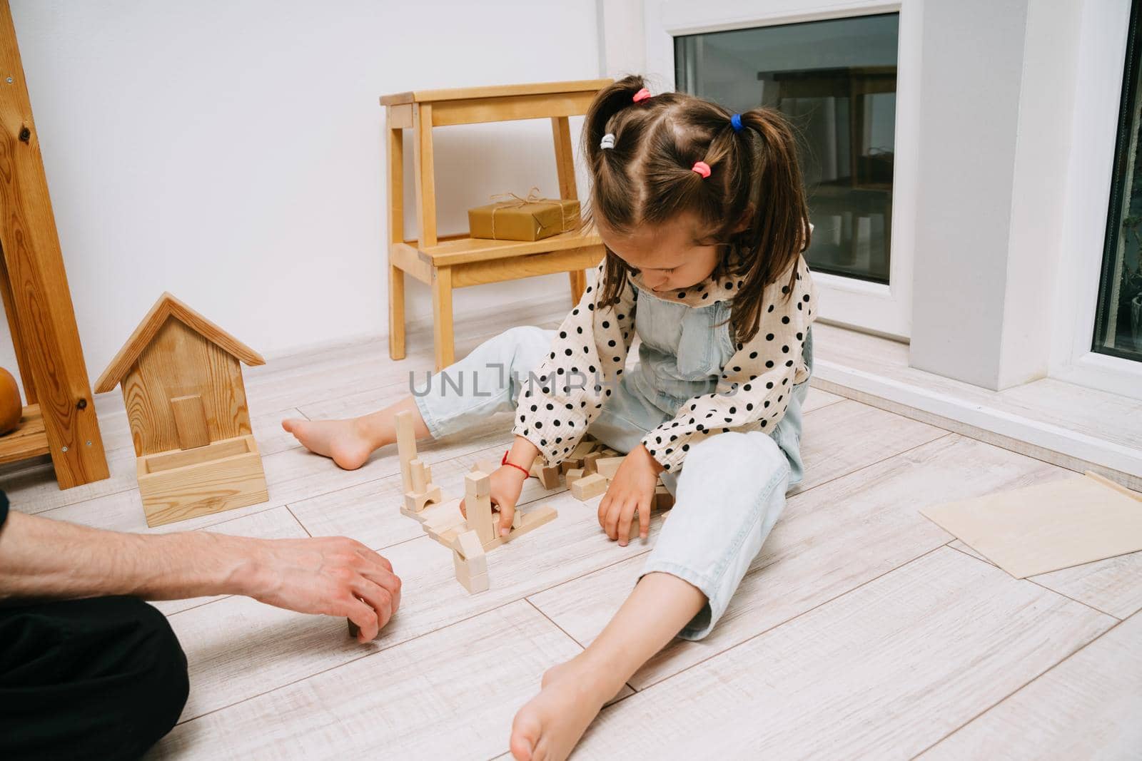 A little girl and her father build a tower out of wooden cubes. Playing with father. Happy Father's Day.