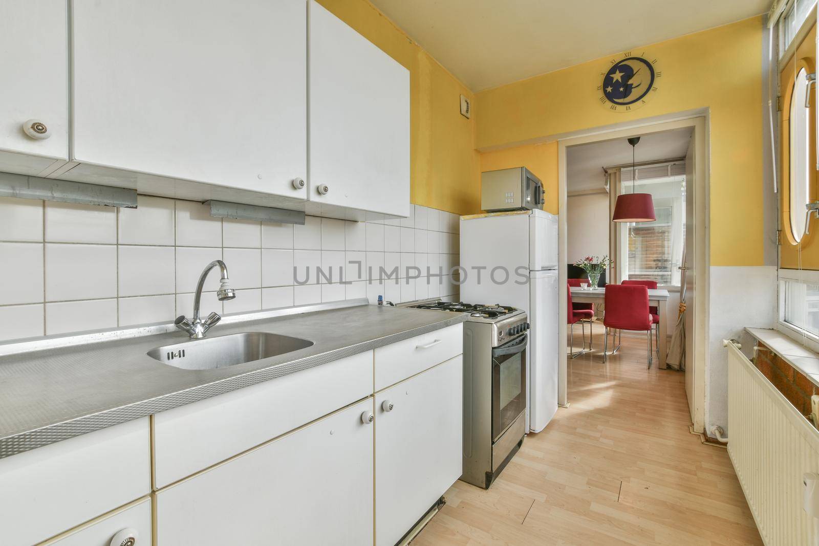 Long modern kitchen in front of a long large window with beautiful parquet flooring