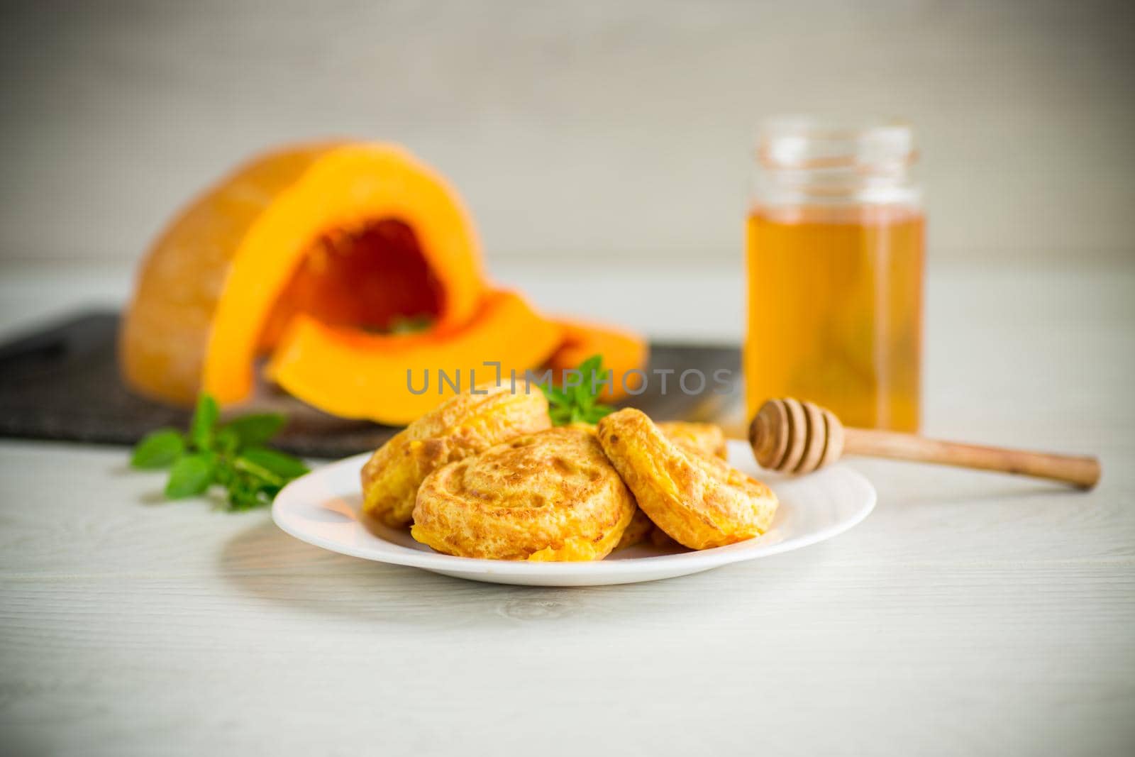 sweet lush pumpkin pancakes with honey in a plate on a wooden table