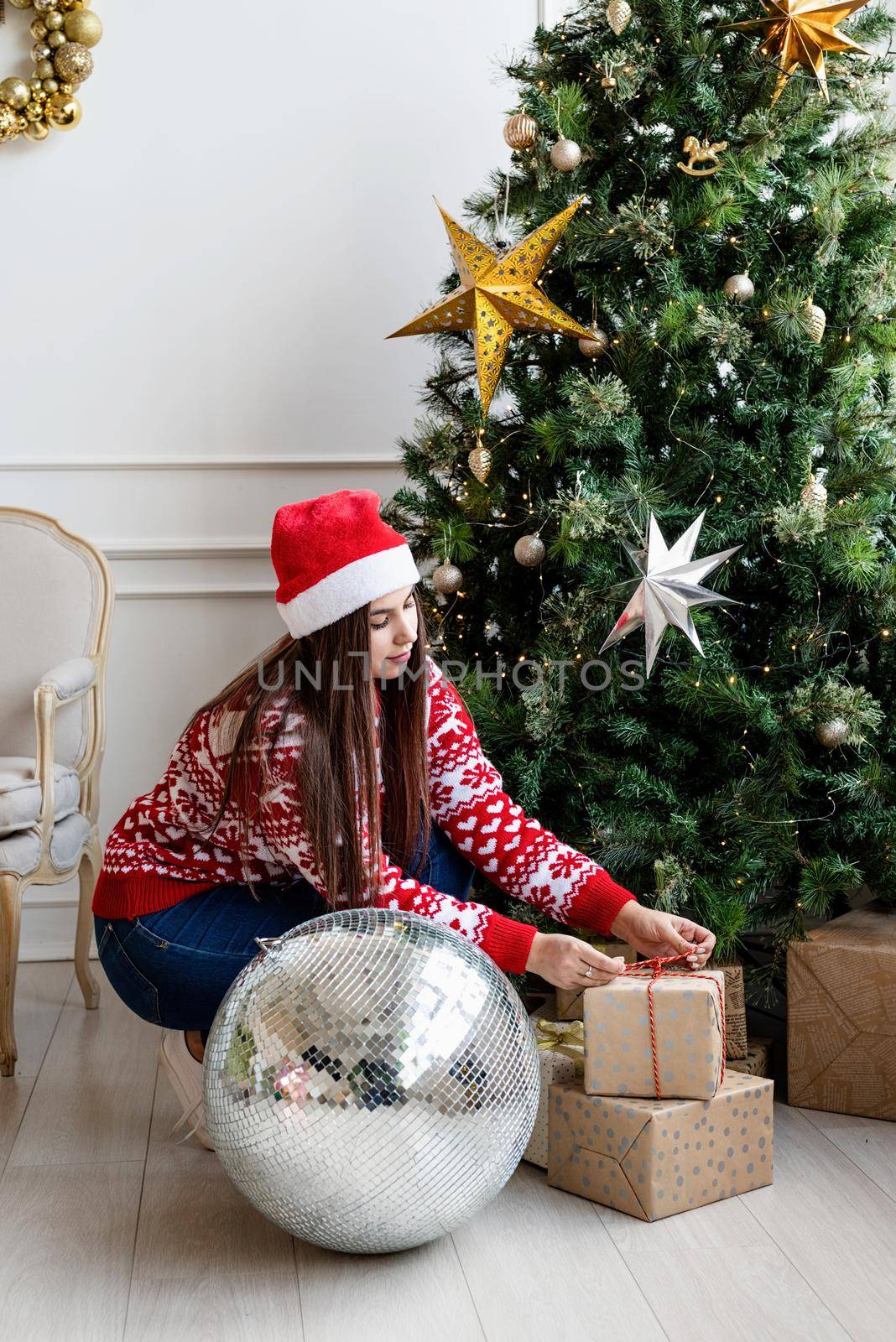 Packaging holiday gifts. Christmas gift wrapping. Young woman in red sweater holding christmas gifts