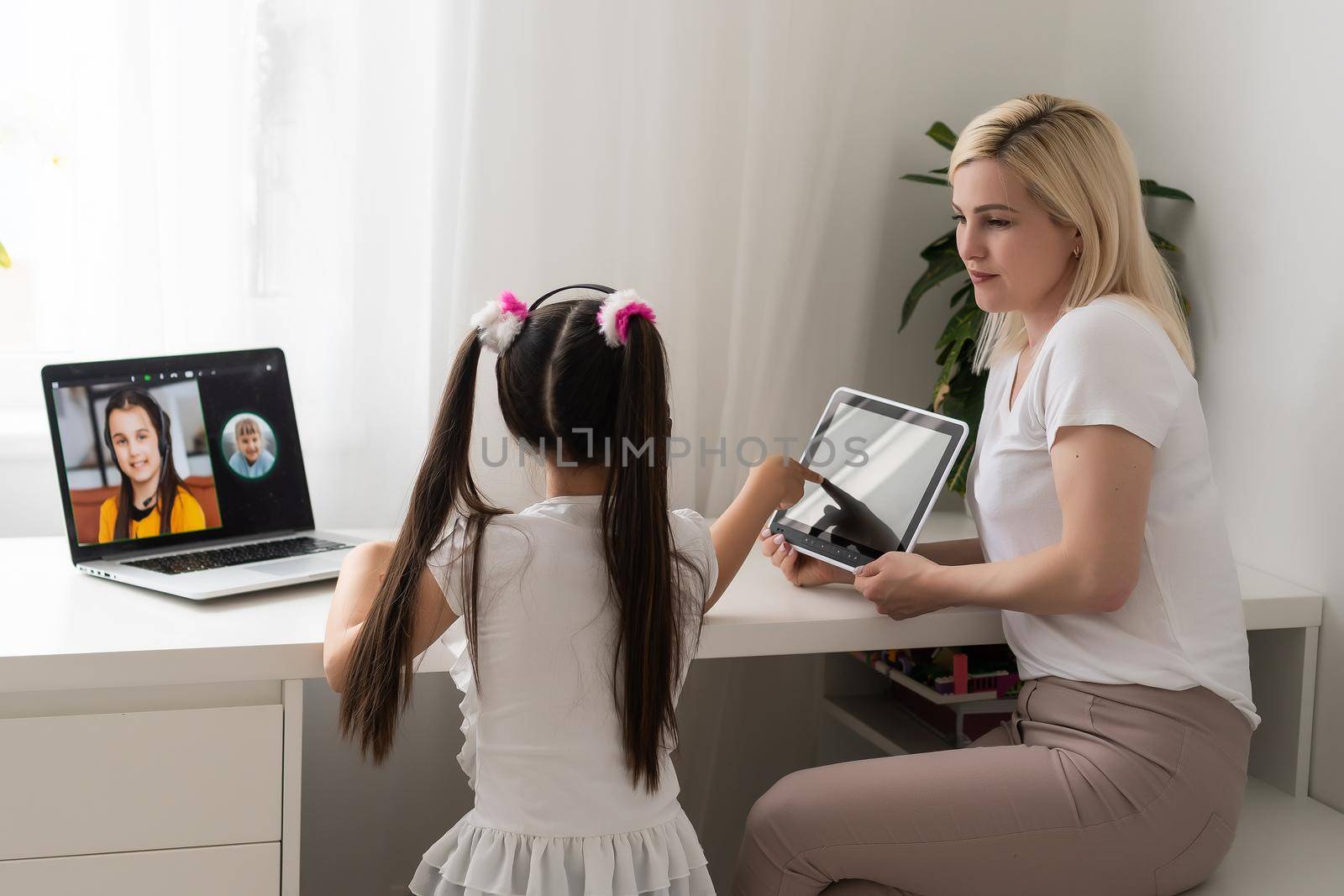Beautiful young mother helping her younger daughter with homework