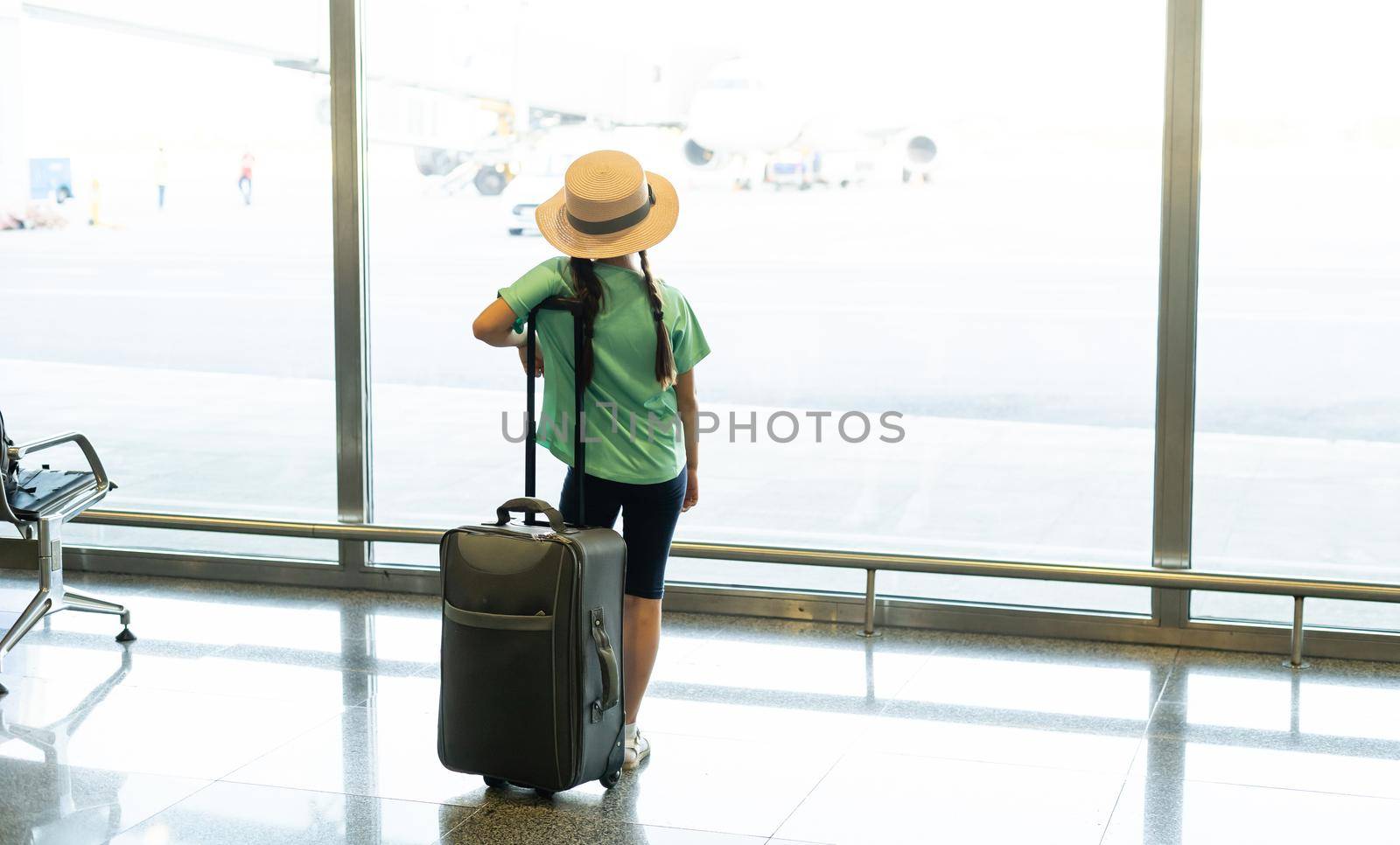 tourism, vacation, childhood and transportation concept - smiling little girl with travel bag, ticket and passport over airport background