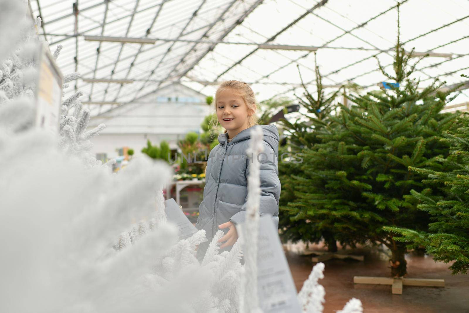 A girl and a white christmas artificial trees for sale at a shop