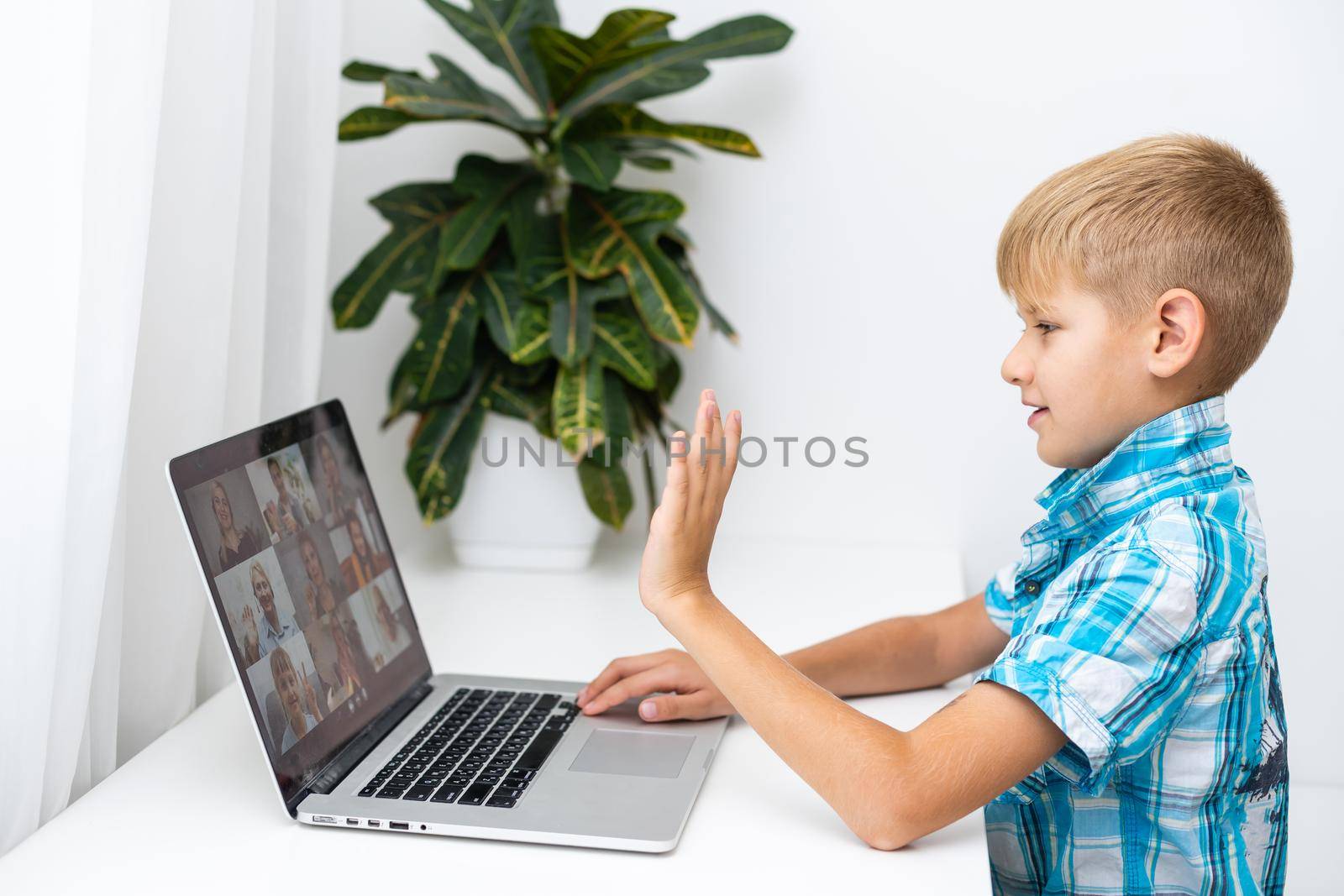 Boy video conferencing with tutor on laptop at home. Distance education concept