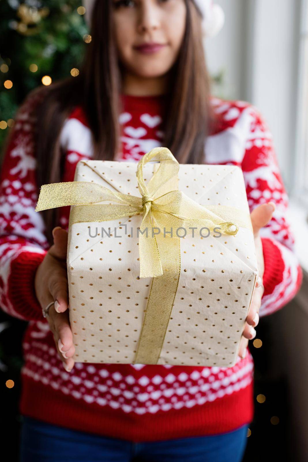 Packaging holiday gifts. Christmas gift wrapping. Young woman in red sweater holding christmas gifts